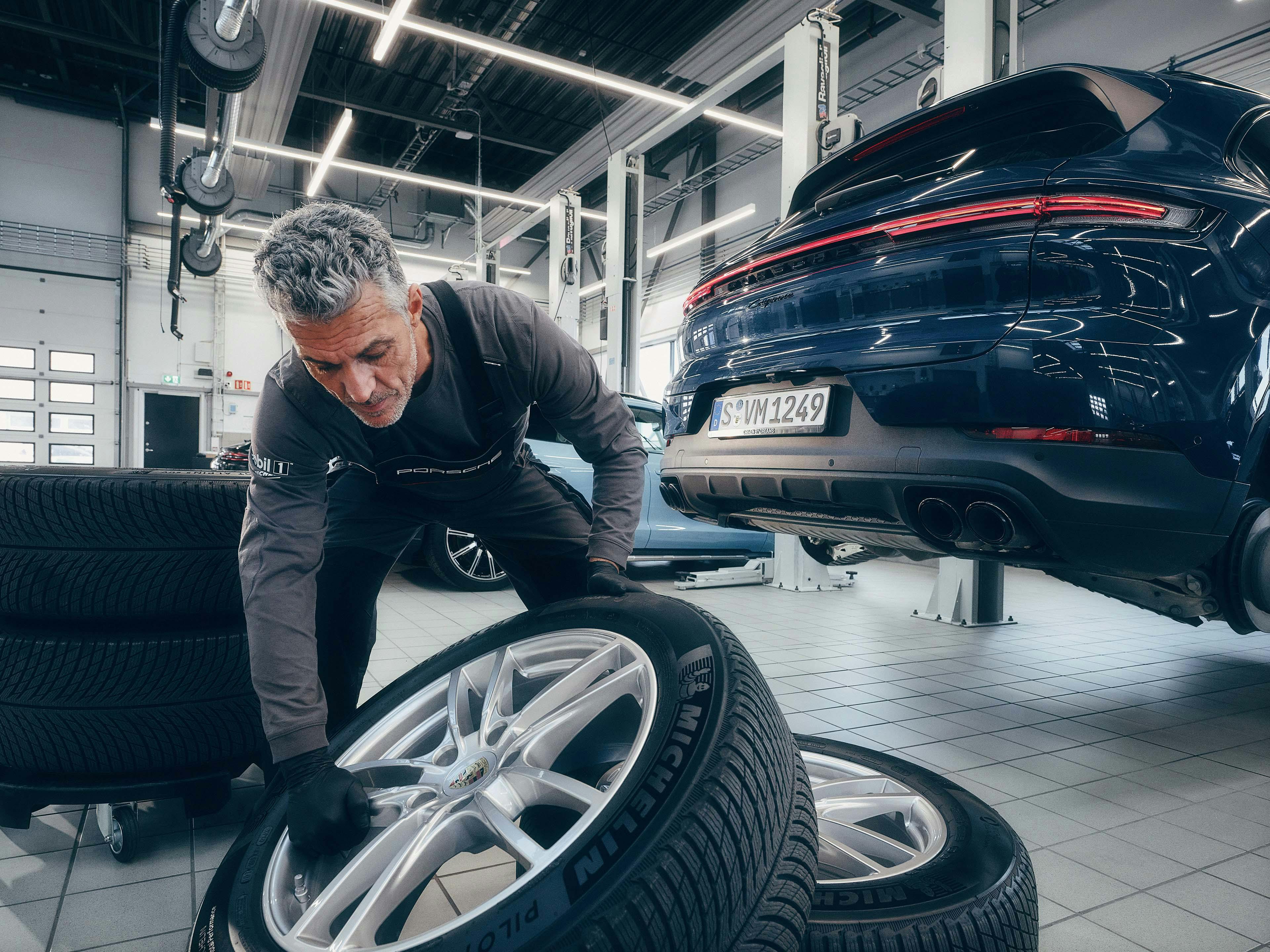 Een man in een Porsche werkplaats die banden aan het vervangen is