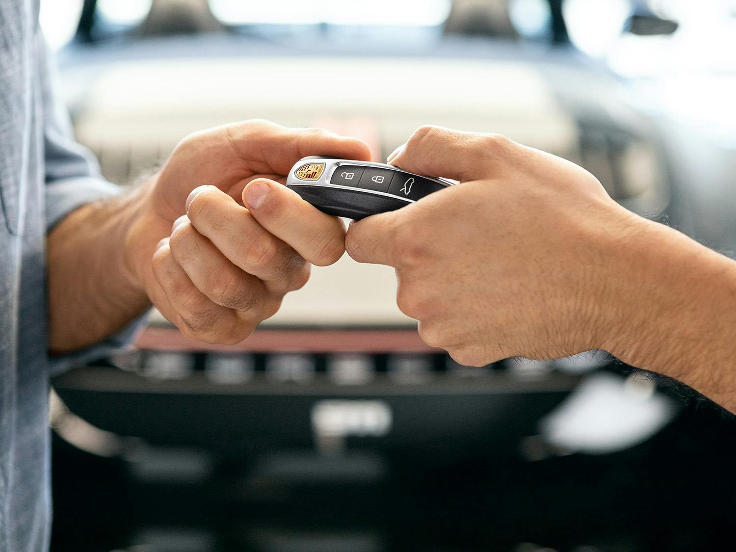 Two hands exchanging a Porsche key fob.