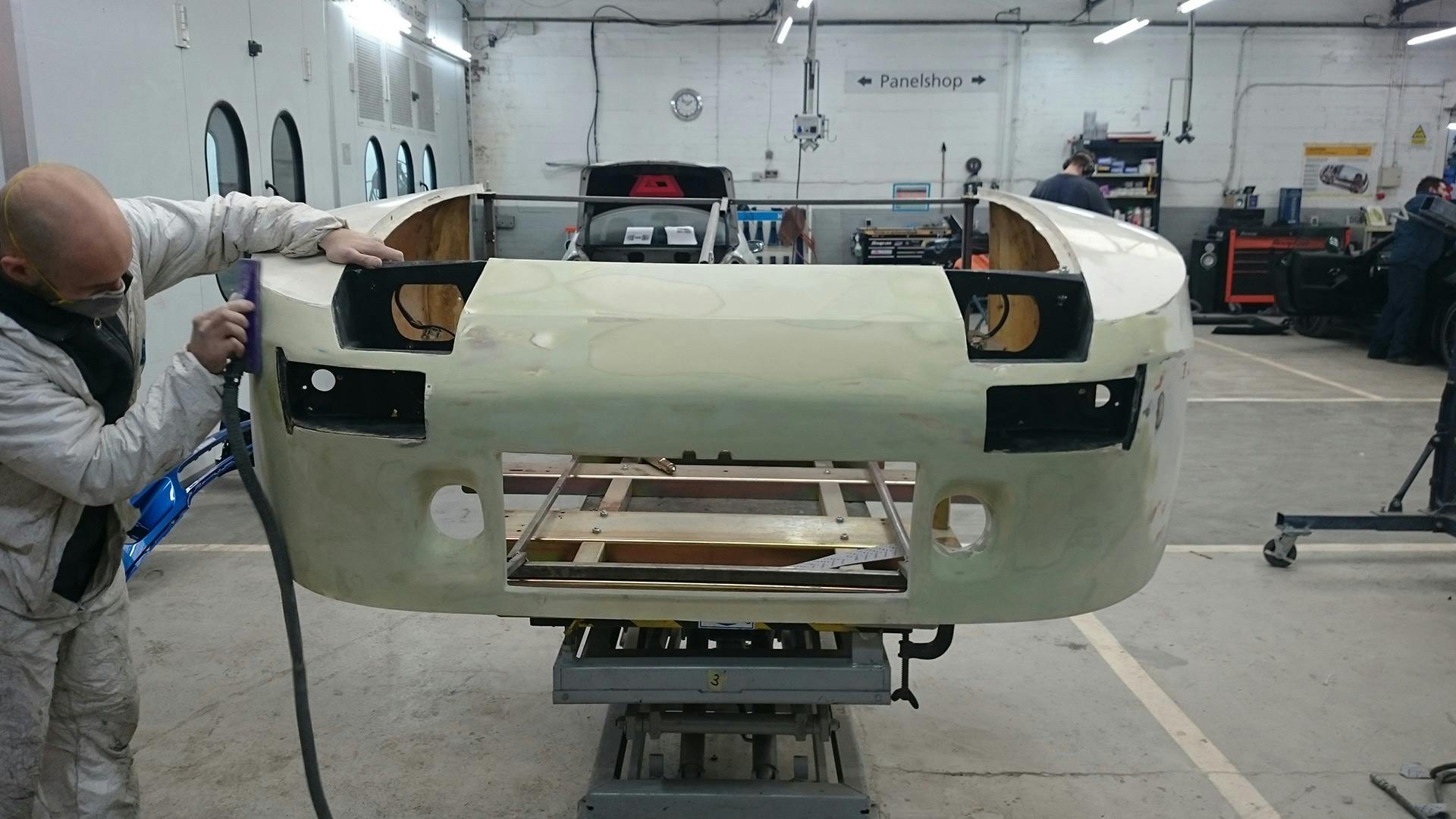 Employee working on the front body of the Porsche 924 GTP doing body work.