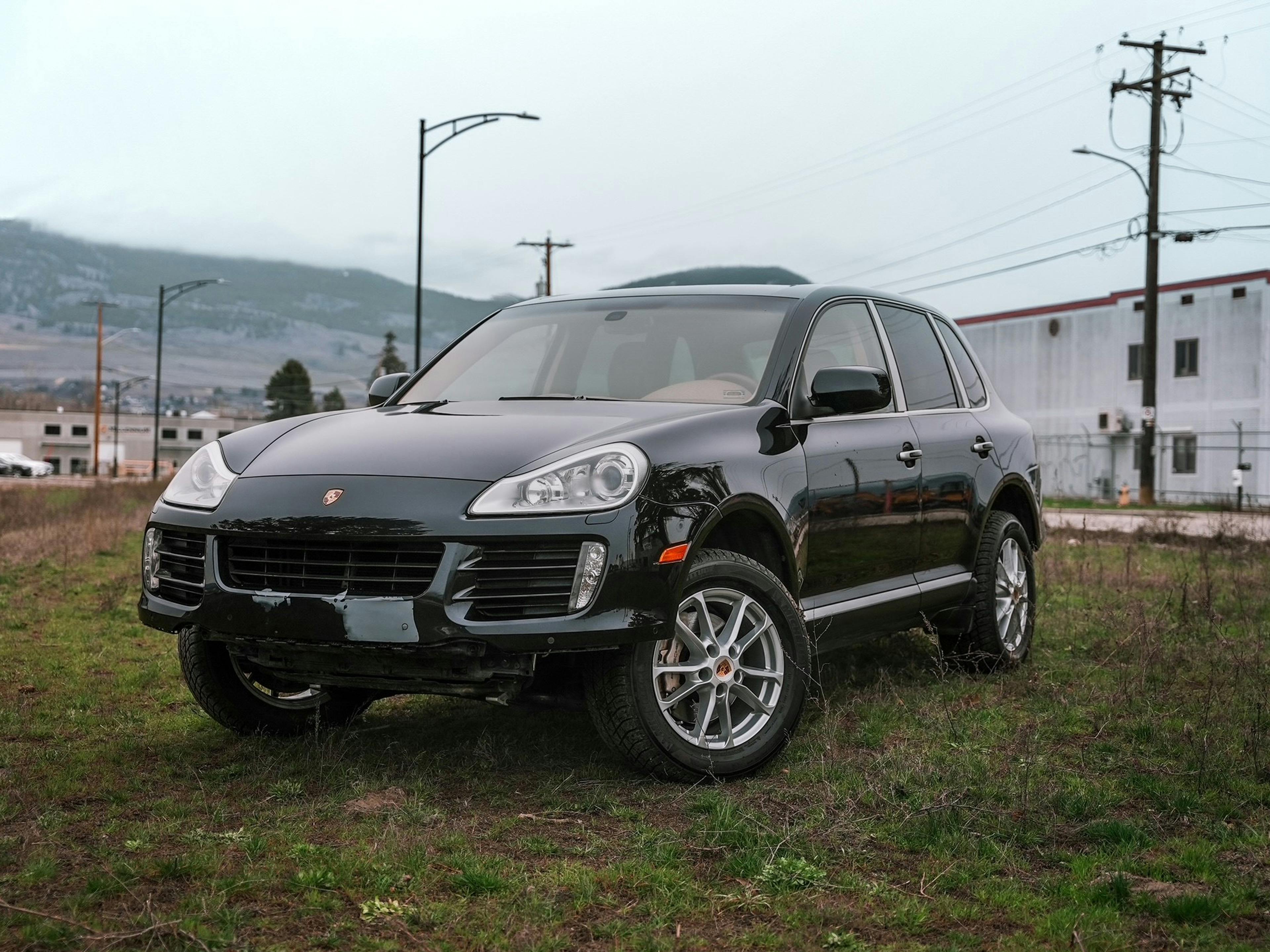 Kelowna – A black Porsche Cayenne on grass next to a road.