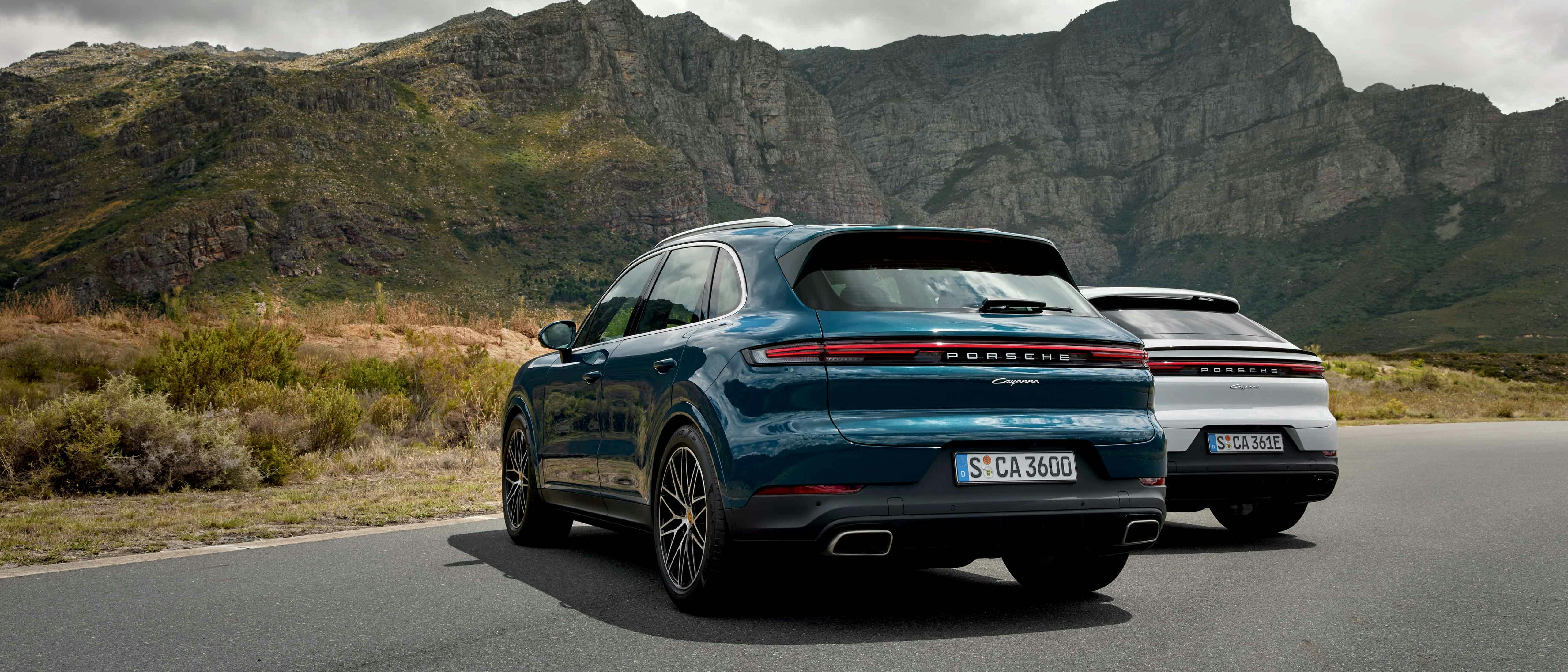 Två Porsche Cayenne parkerade framför ett berg.