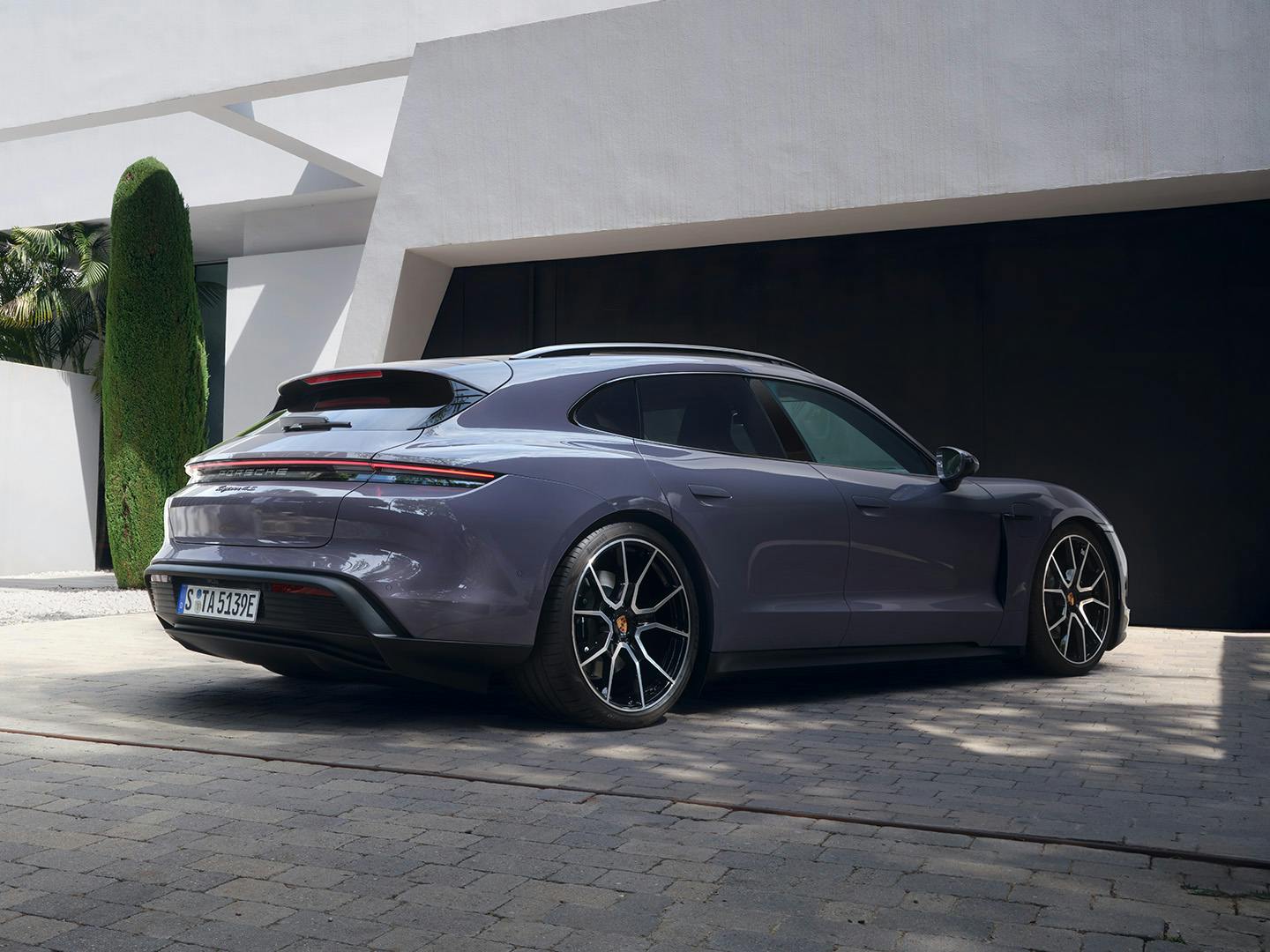 A Taycan 4S Sport Turismo in Provence parked in the driveway of a trendy white modern house.
