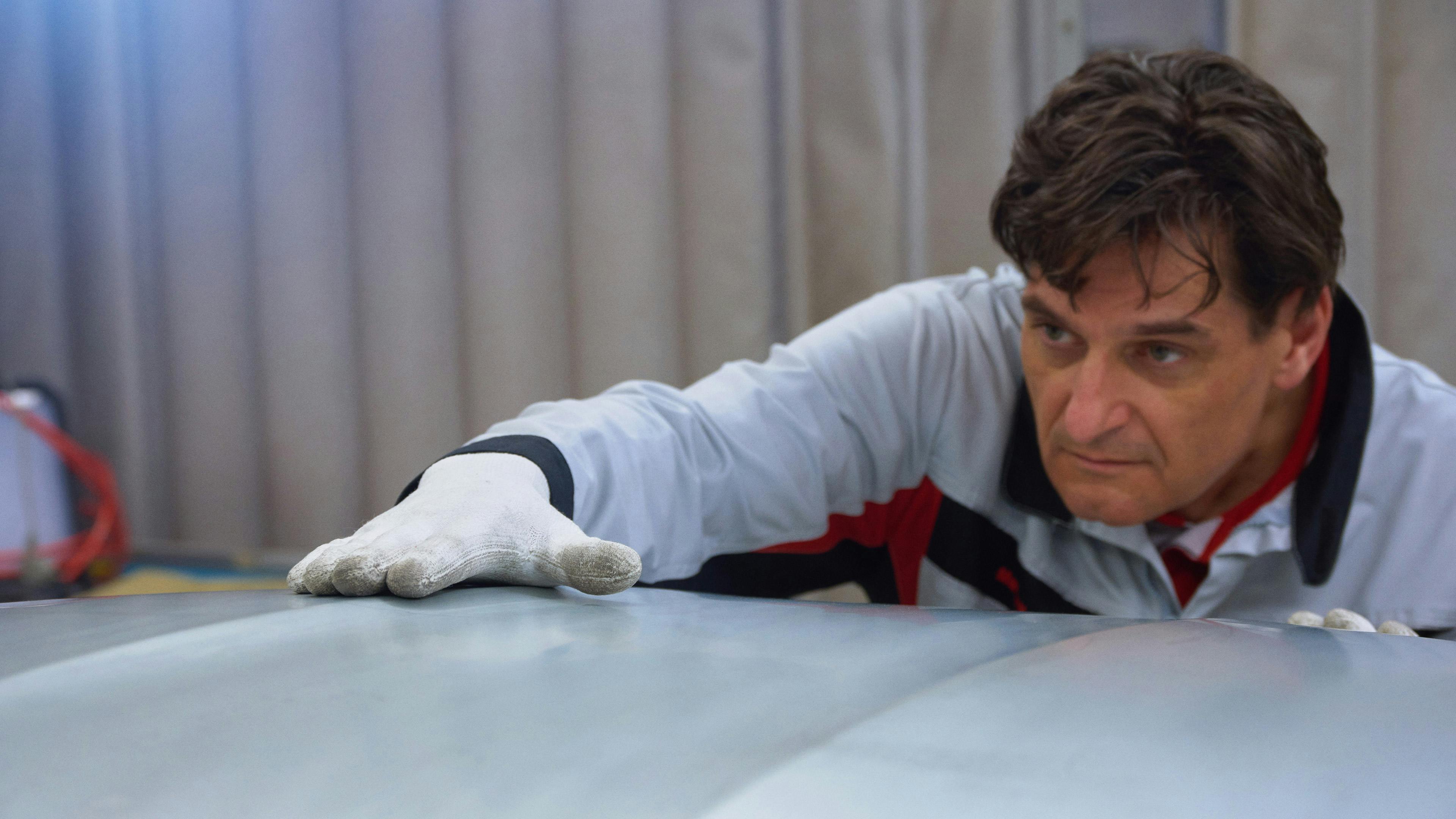 Mechanic with white glove strokes rear lid.