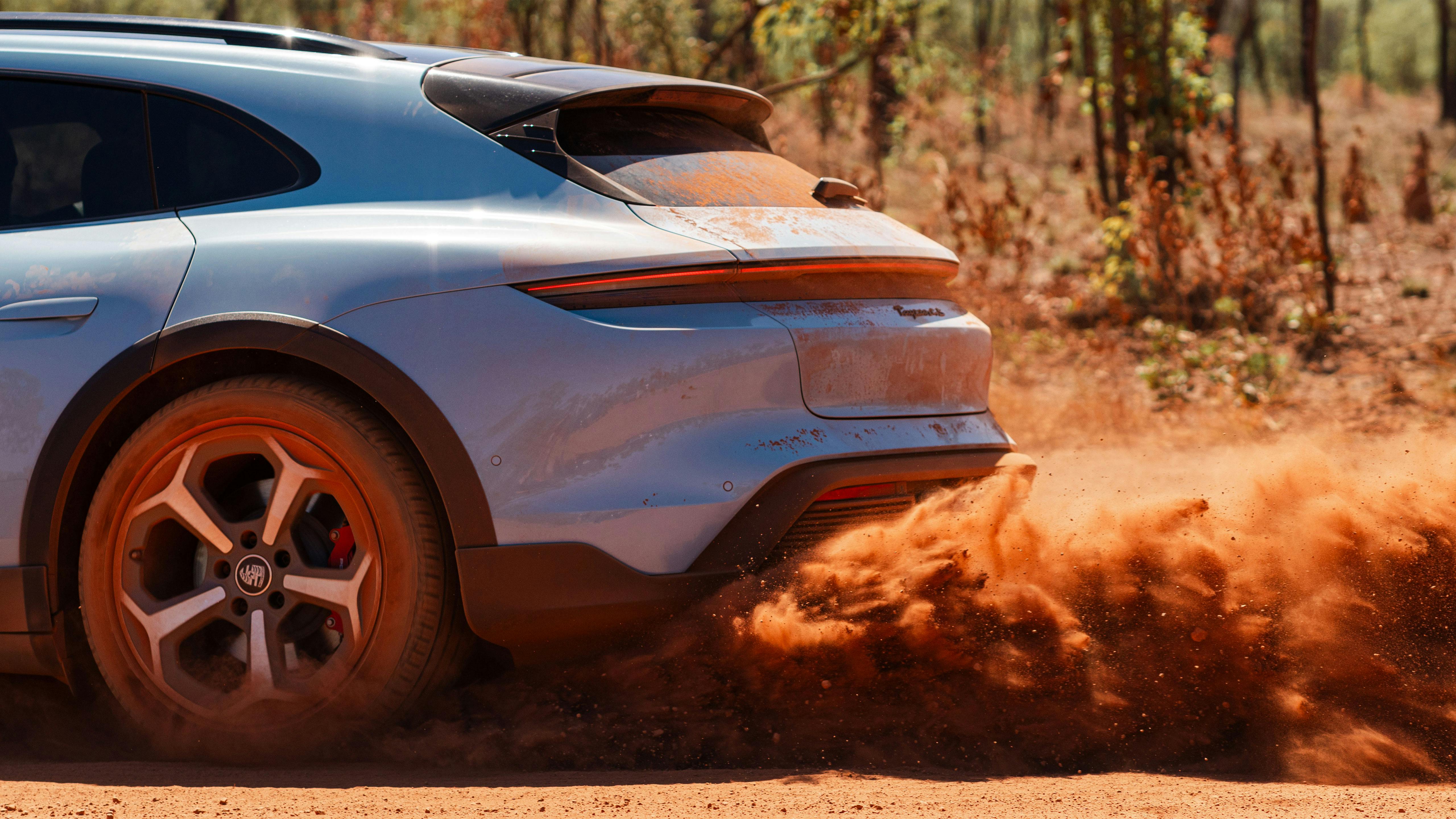 Porsche Taycan kicking up red dirt in the outback