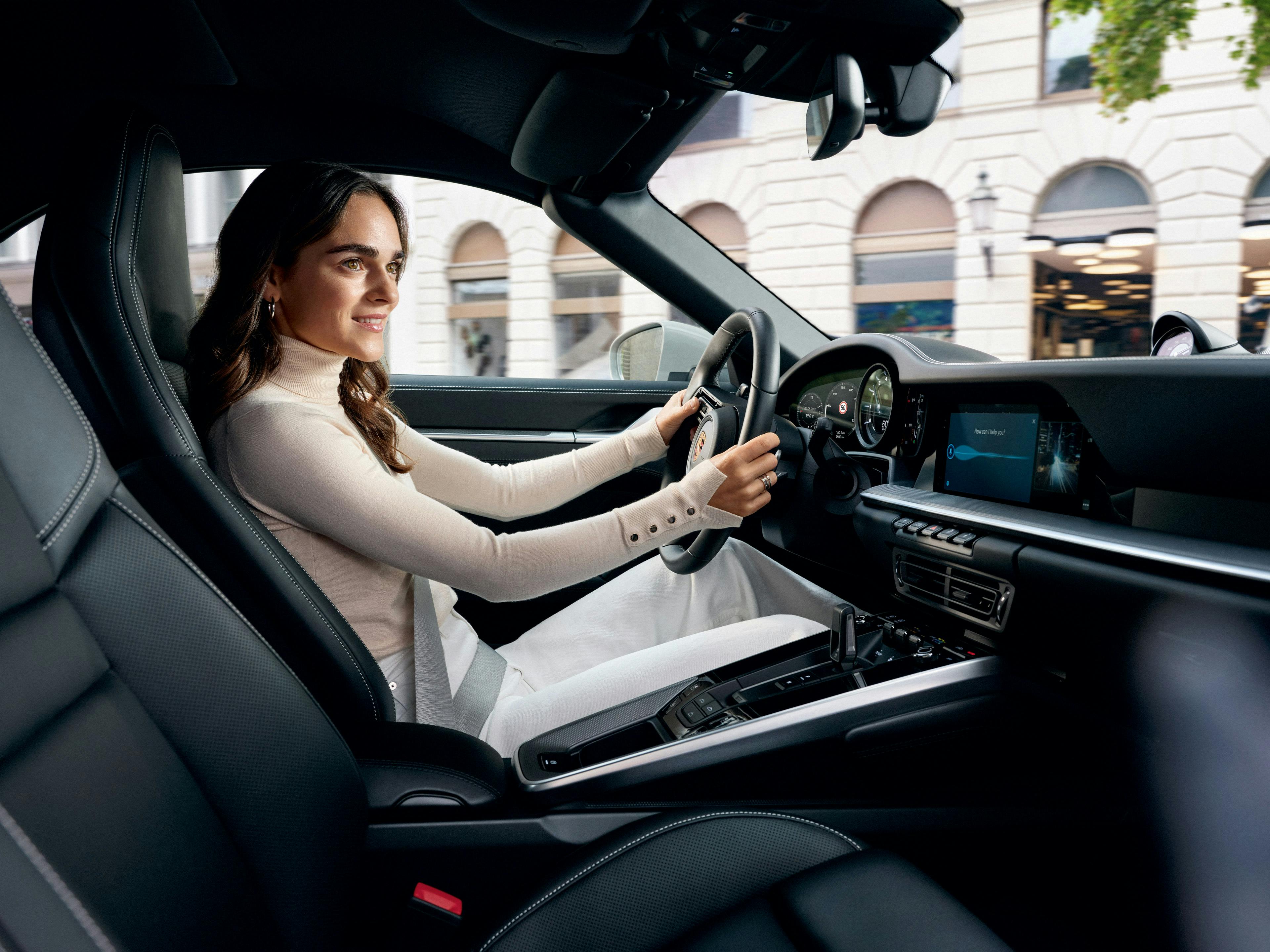 Une femme est assise sur le siège du conducteur, le volant à la main.
