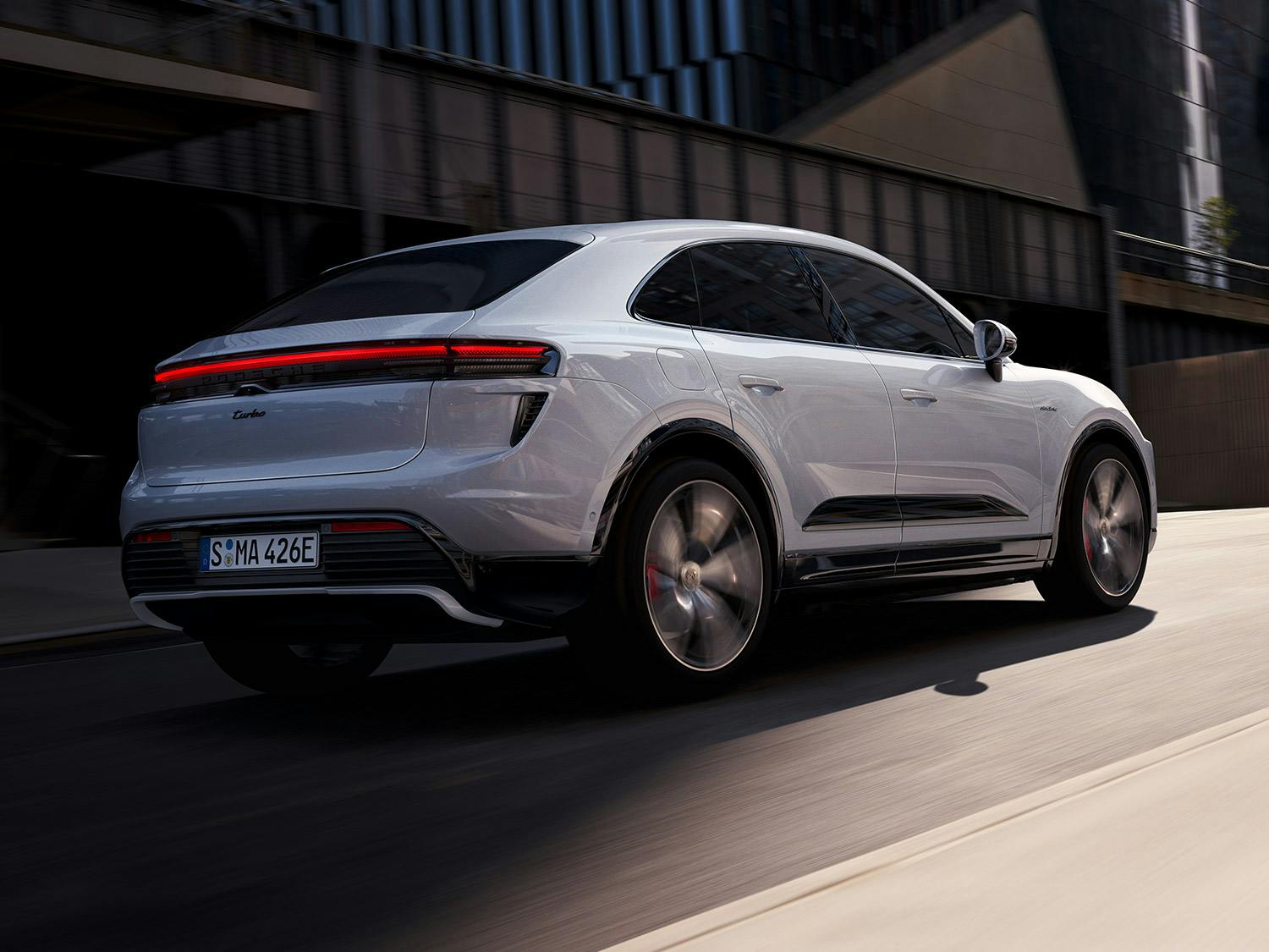 Un Porsche Mcana Turbo Electric roulant dans une rue.