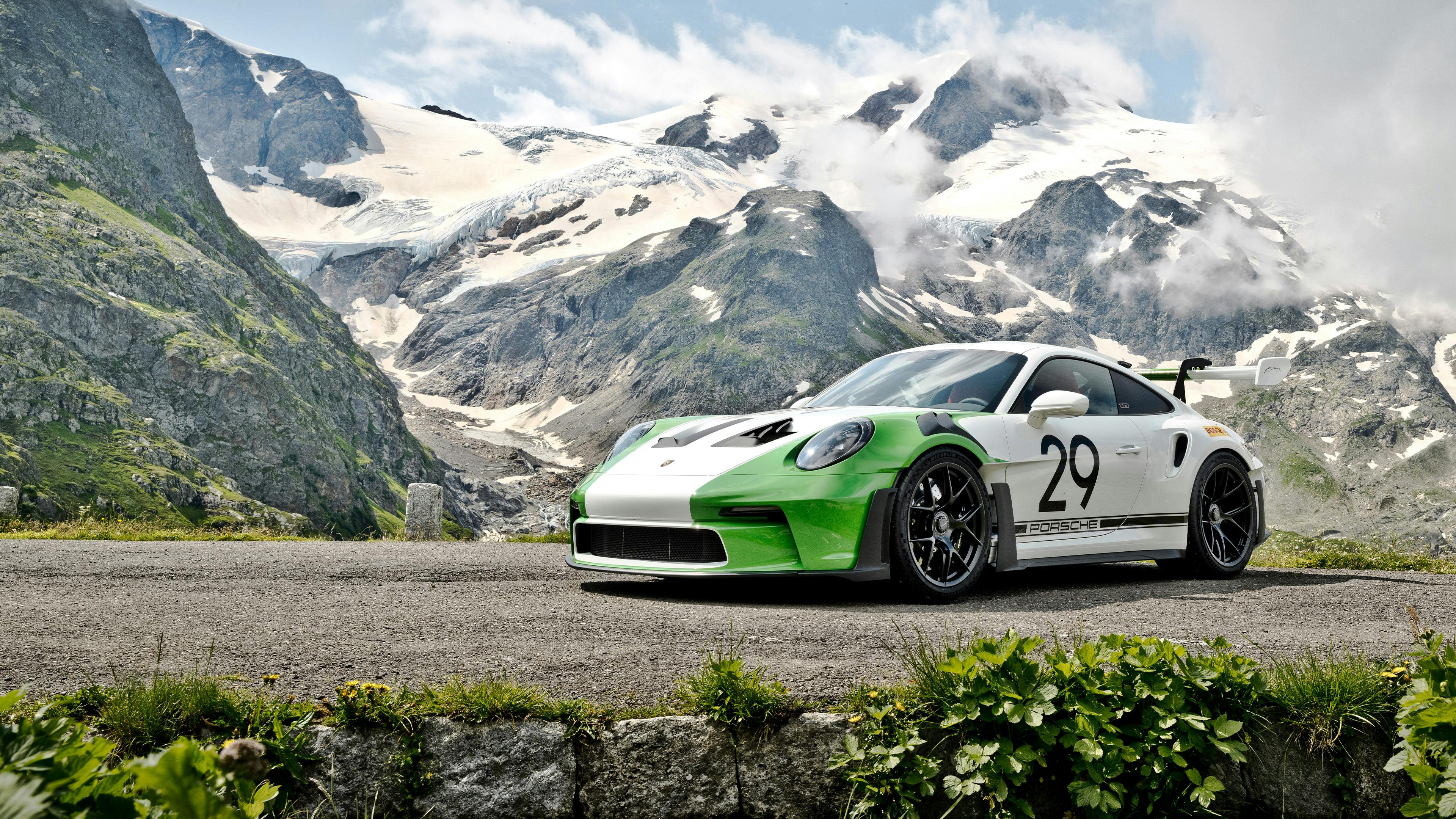 A 911 GT3 RS Tribute to Jo Siffert coloured in Purewhite and Vipergreen and historic Starting Number 29 and Porsche lettering on doors in front of a mountainrange.