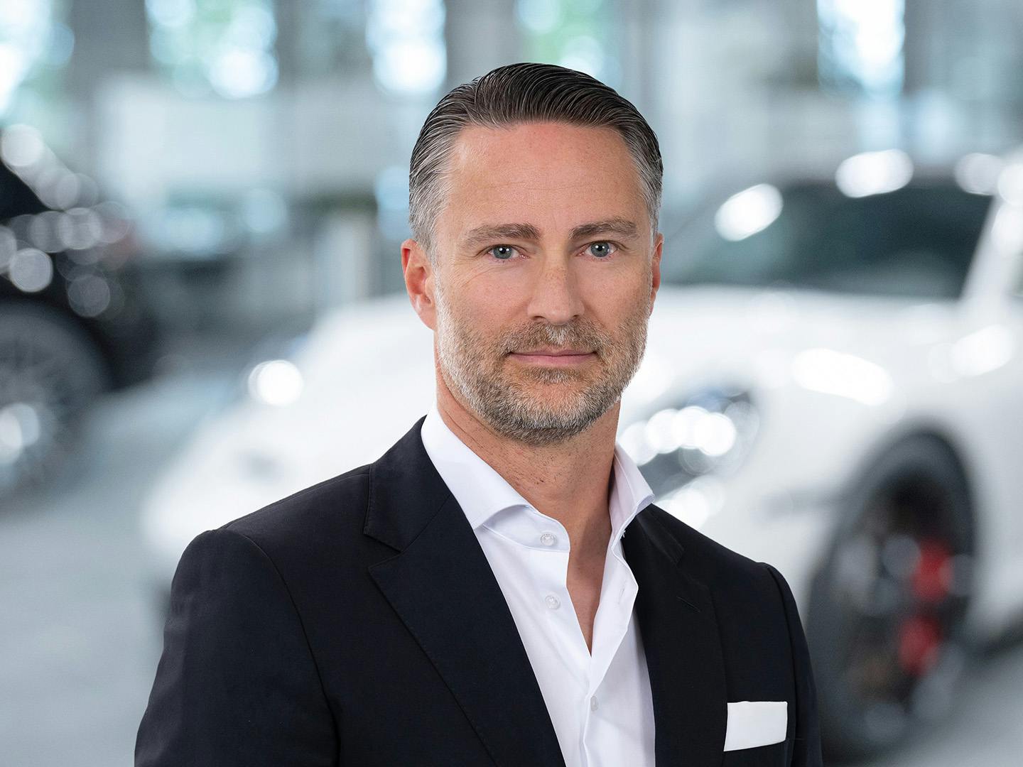 Porsche Mitarbeiterin berät einen Kunden der in einem Porsche Fahrzeug sitzt.