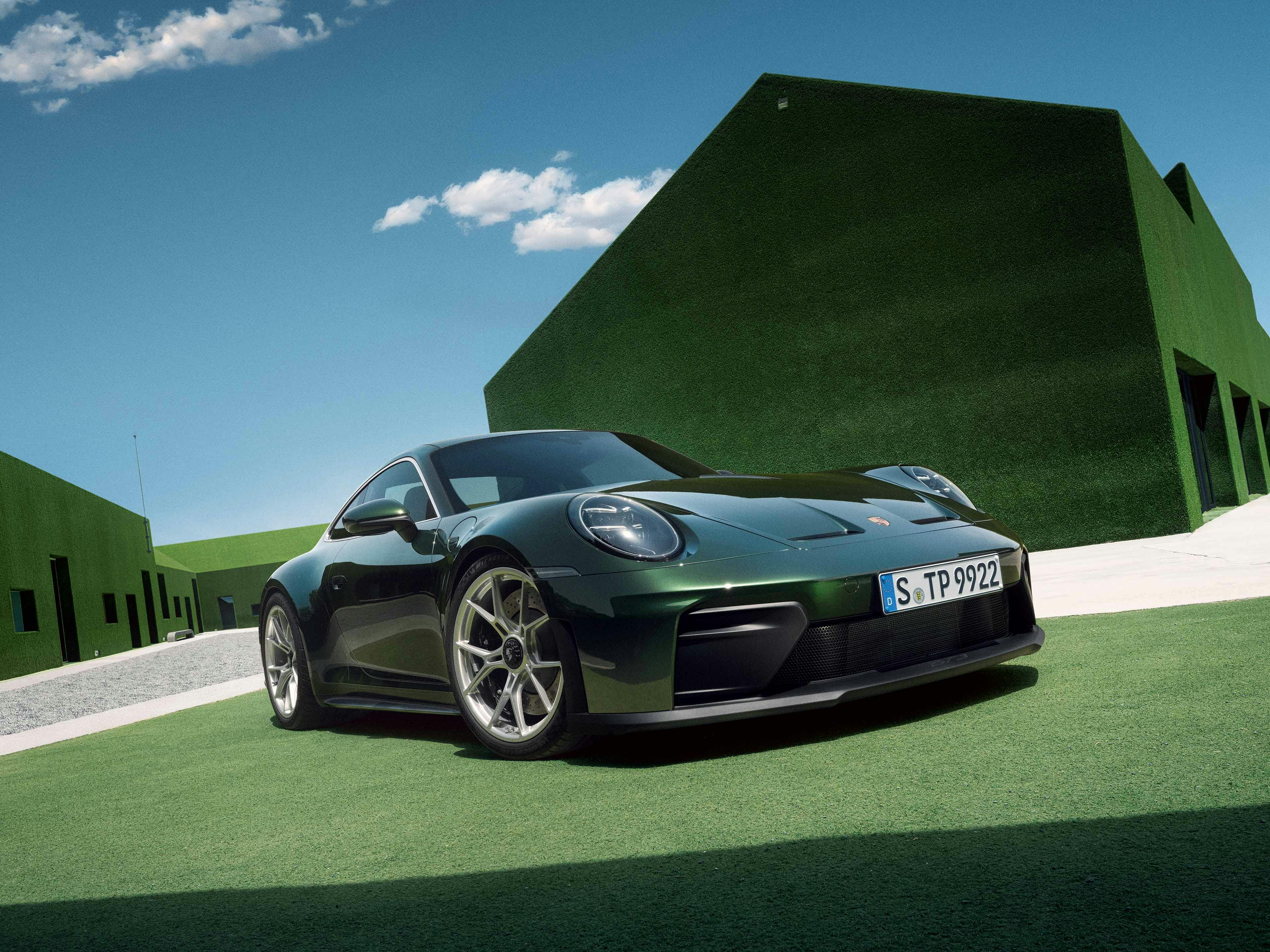 Porsche 911 GT3 Touring staat geparkeerd voor groene huizen.