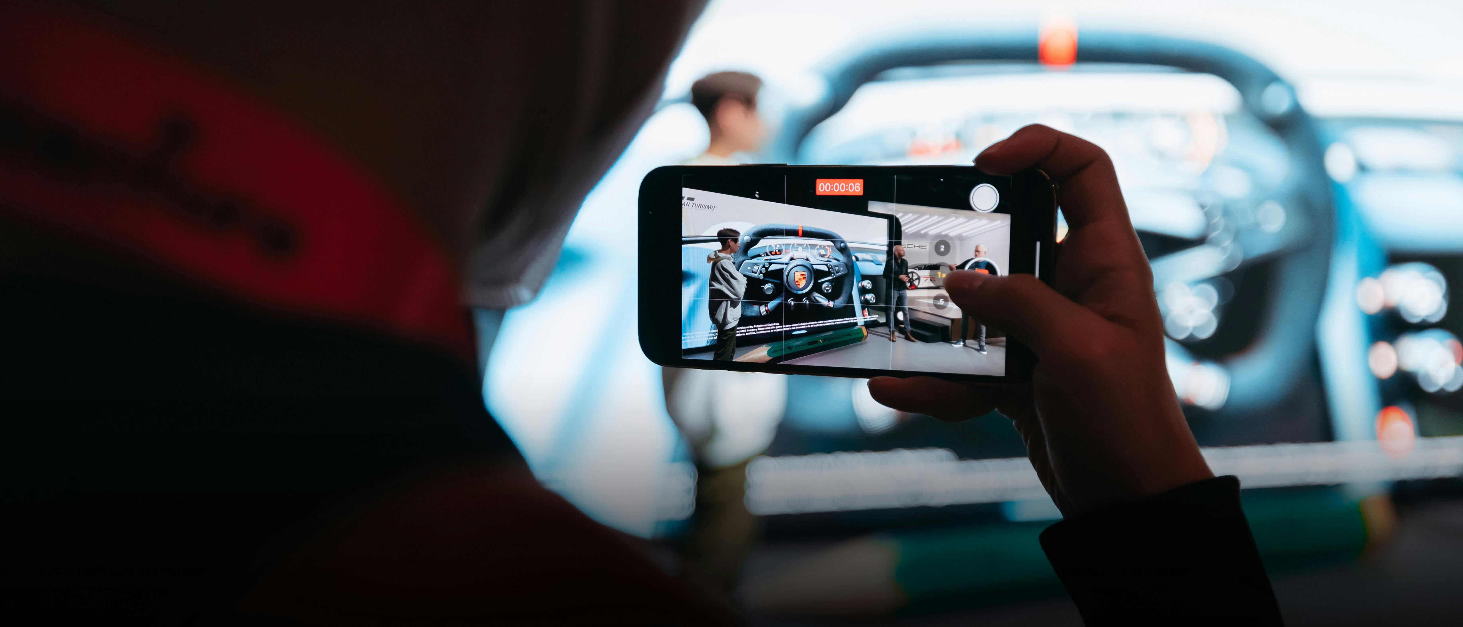 Ein Porsche Mitarbeiter filmt mit seinem Mobiltelefon einen Gaming-Talk.