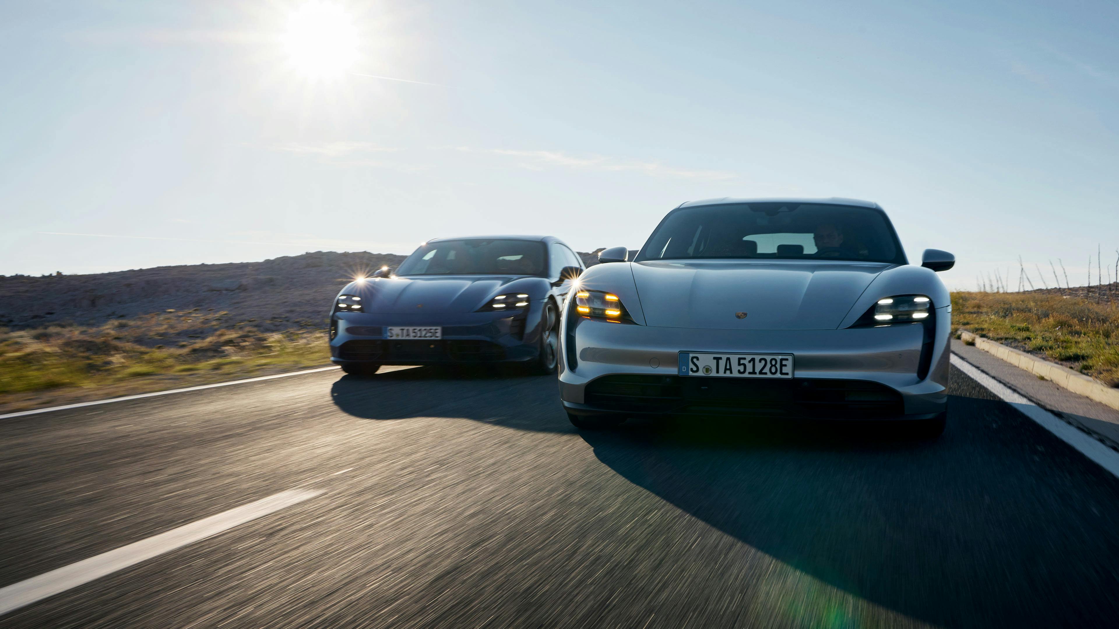 Two Porsche Taycan cars driving on a road.