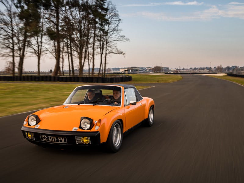 Le véhicule gagnant, une Porsche 914 orange, roule sur le circuit.