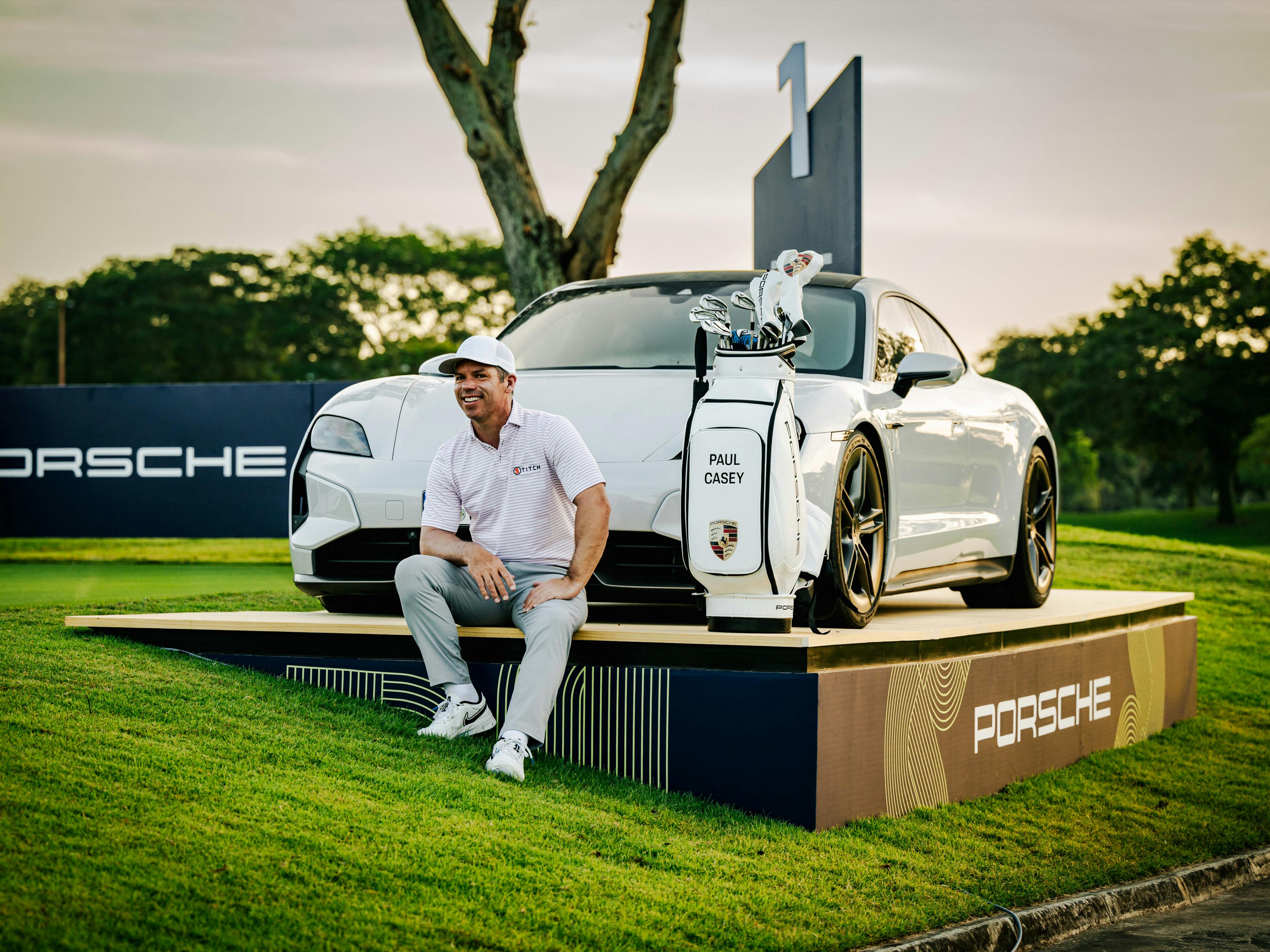 Porsche Markenbotschafter Paul Casey sitzt vor einem Taycan.