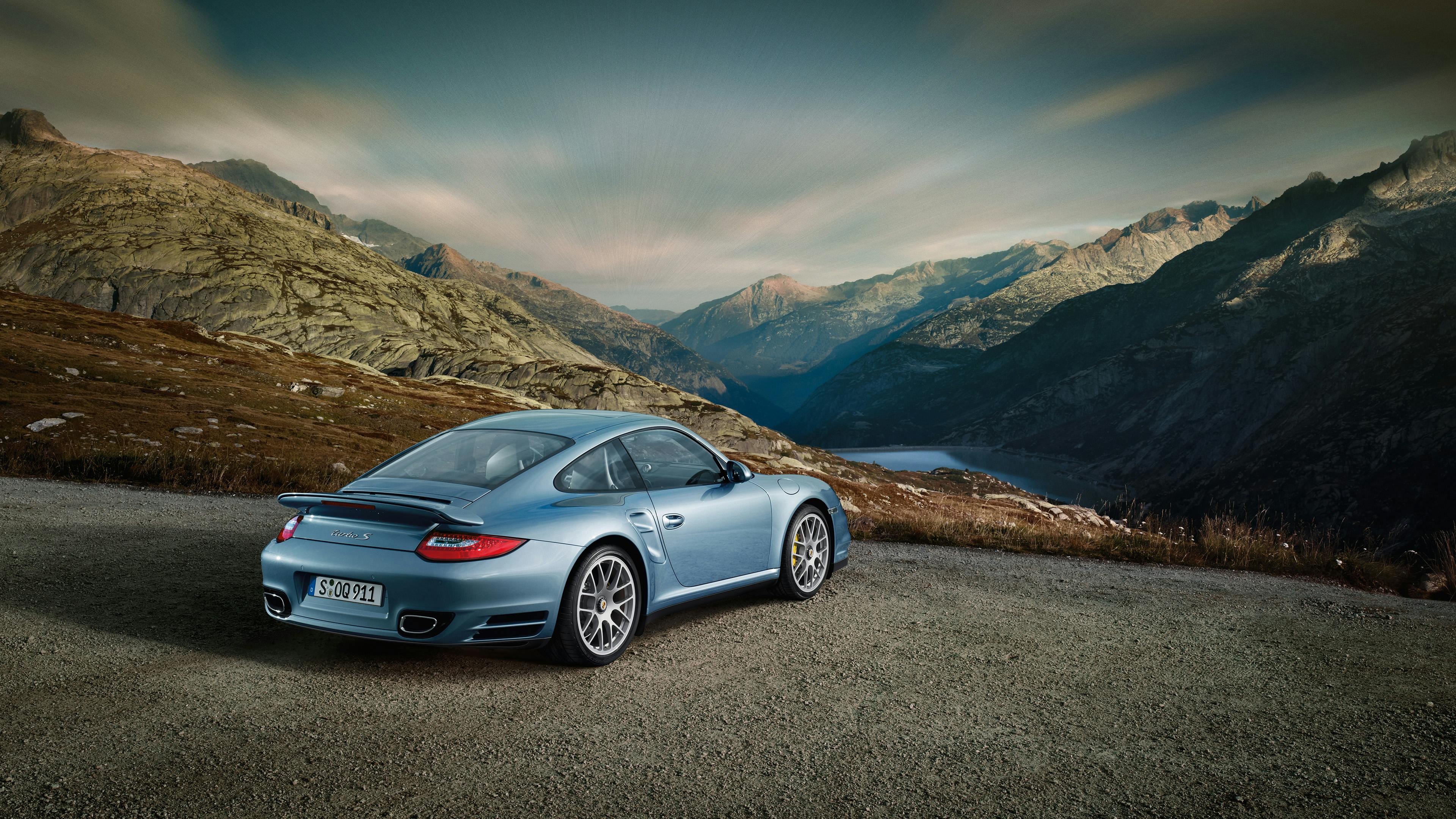 Parked blue 911 Turbo S Coupé in a mountain landscape with mountain lake.
