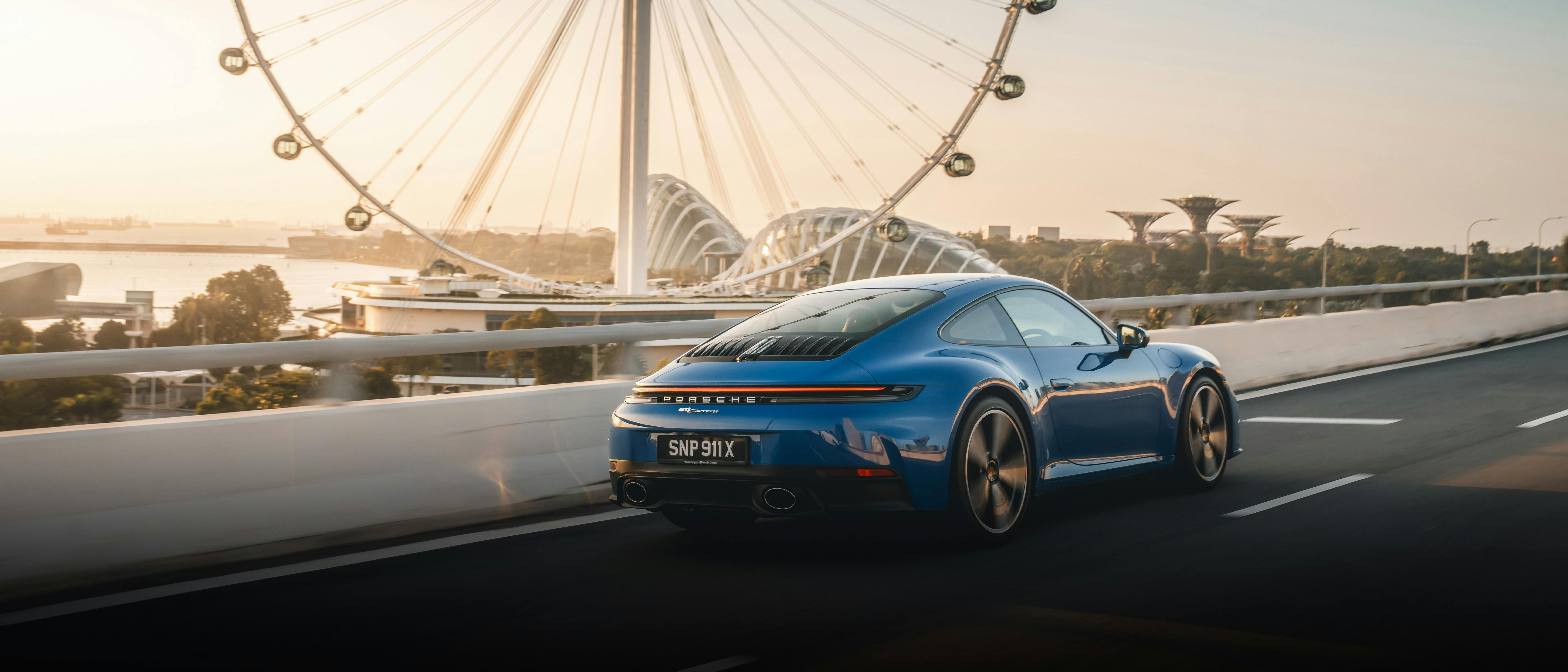 Blue 911 Carrera on the road, set against the Singapore flyer in the background