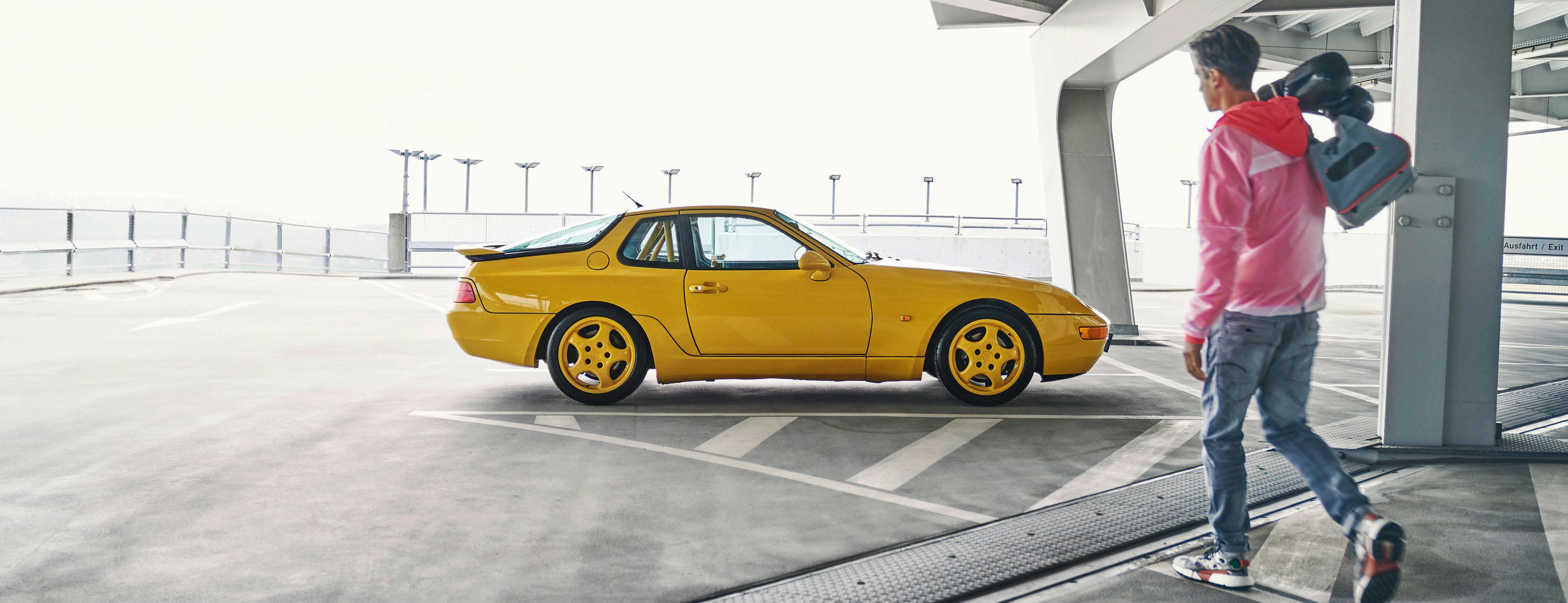 Parkplatzszene: gelber Porsche 968.