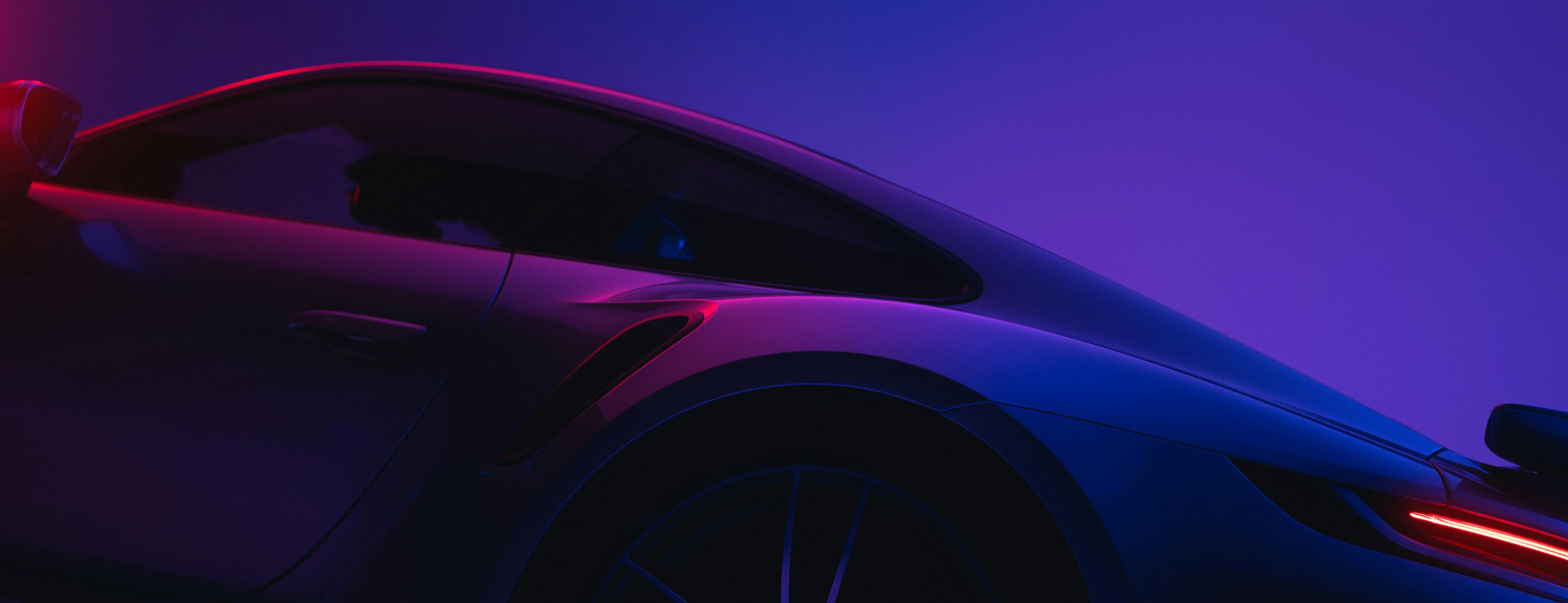 Vue latérale d'une Porsche, éclairée par une lueur futuriste violette et rose.