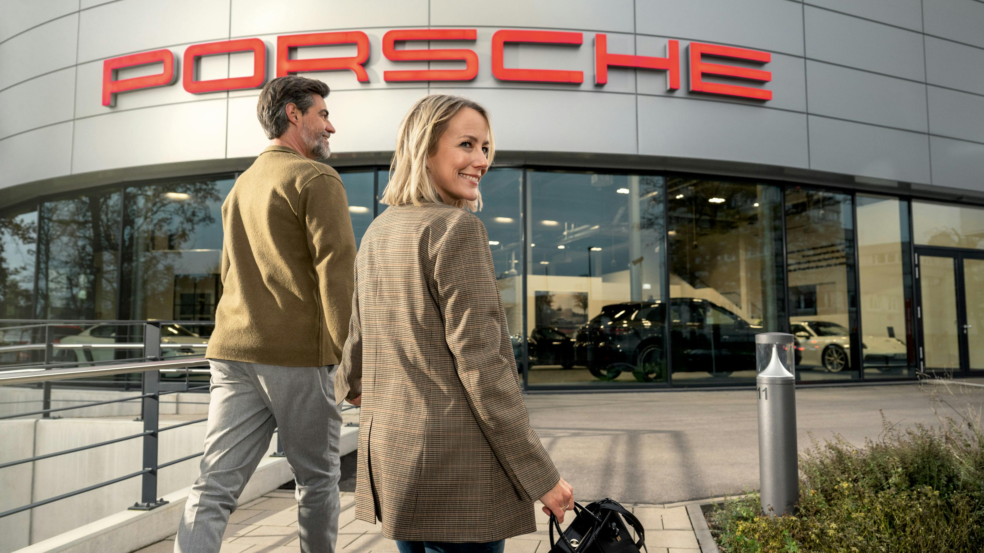 Ein Paar geht Hand in Hand zur Porsche Niederlassung.