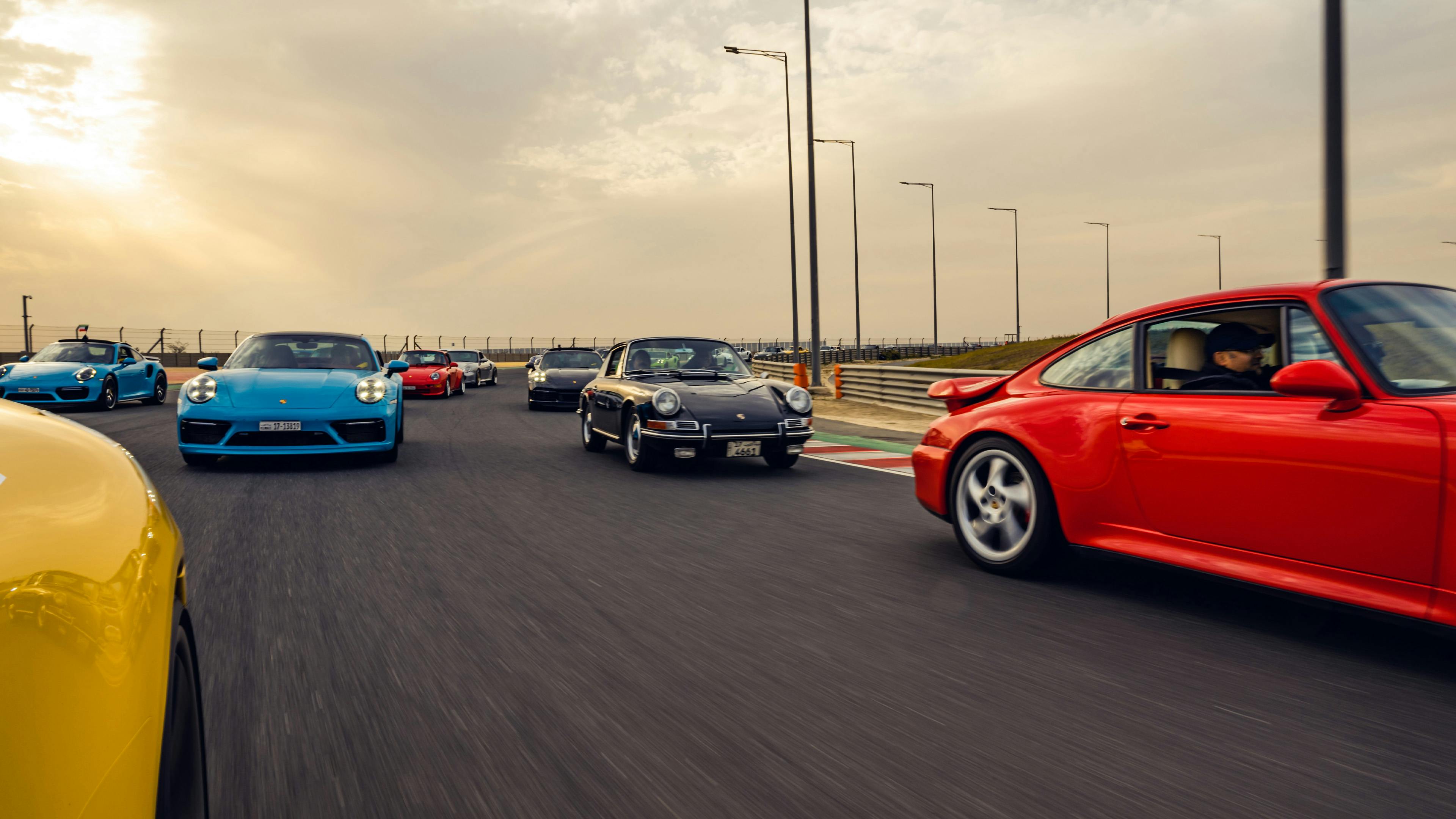 Multicoloured Porsches on a racetrack.