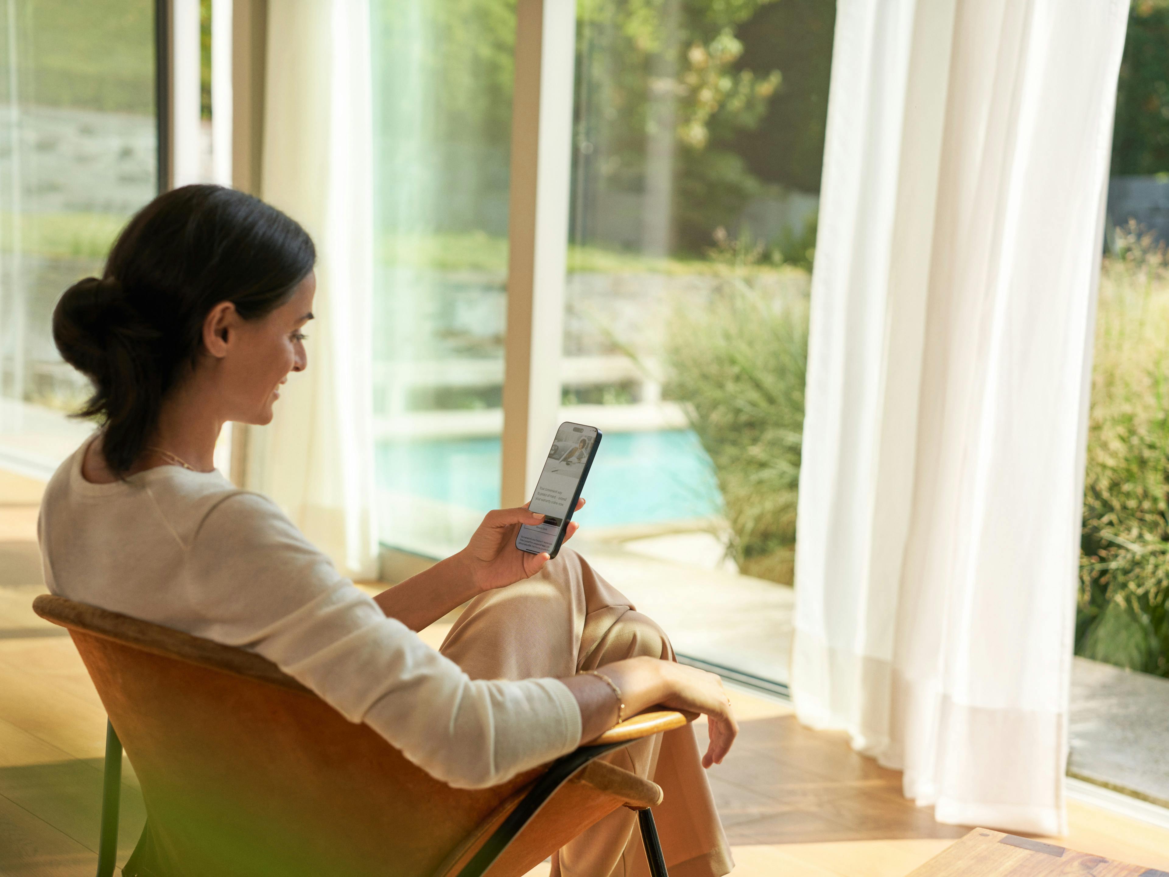 A woman sat in a chair while using her mobile phone.