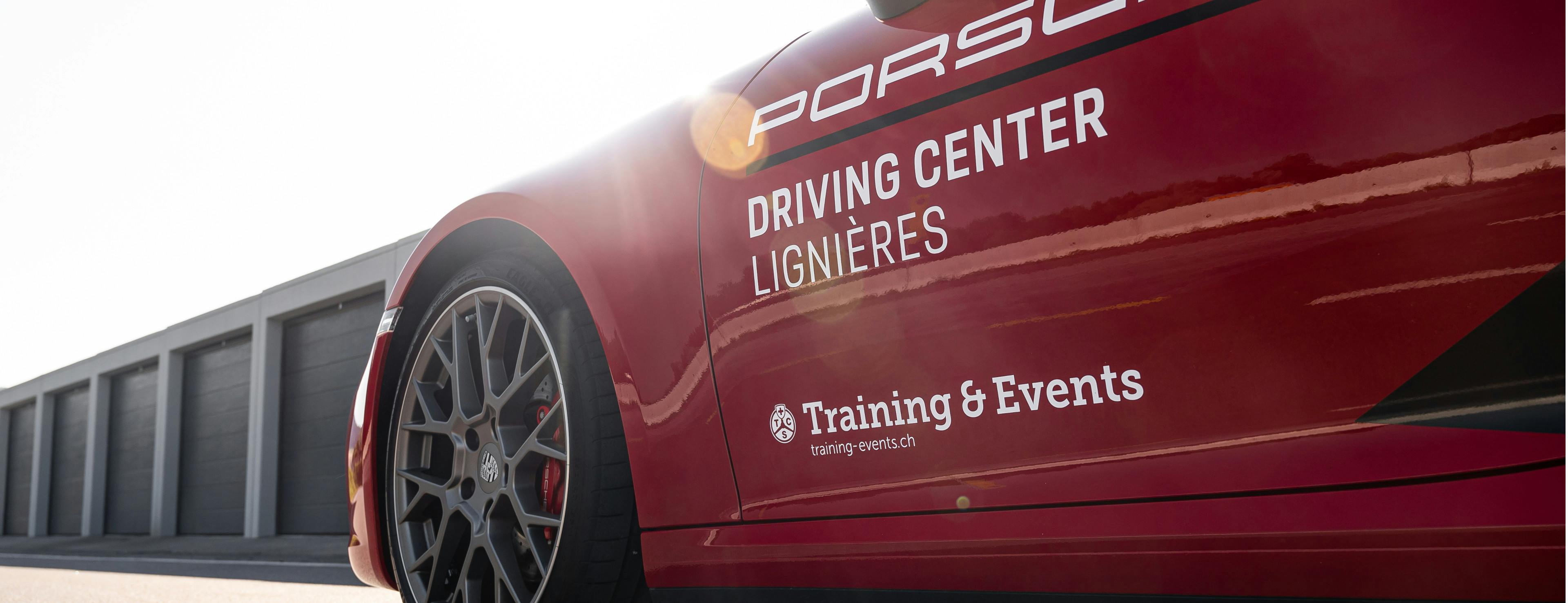 Vue latérale d'une Porsche rouge portant l'inscription Porsche Driving Center Lignières Training & Events.