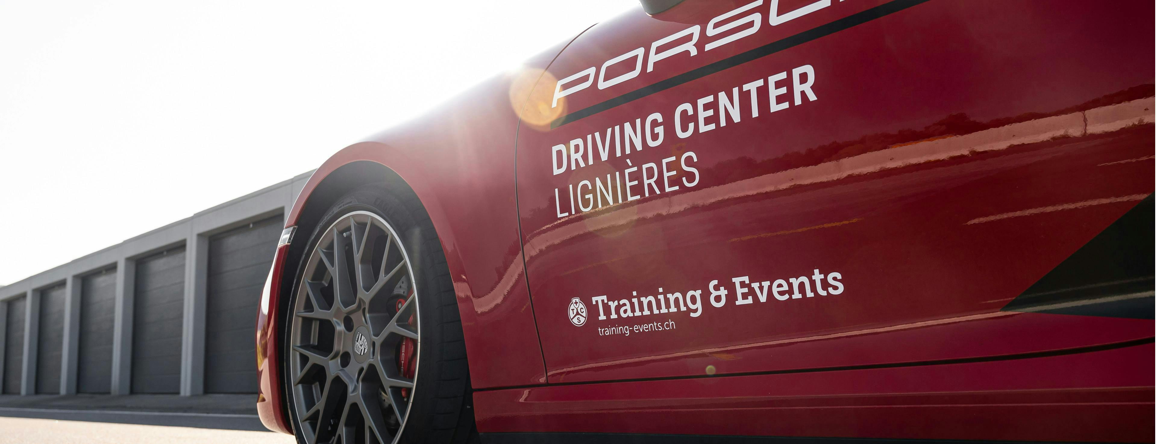 Vista laterale di una Porsche rossa con la scritta Porsche Driving Center Lignières Training & Events.