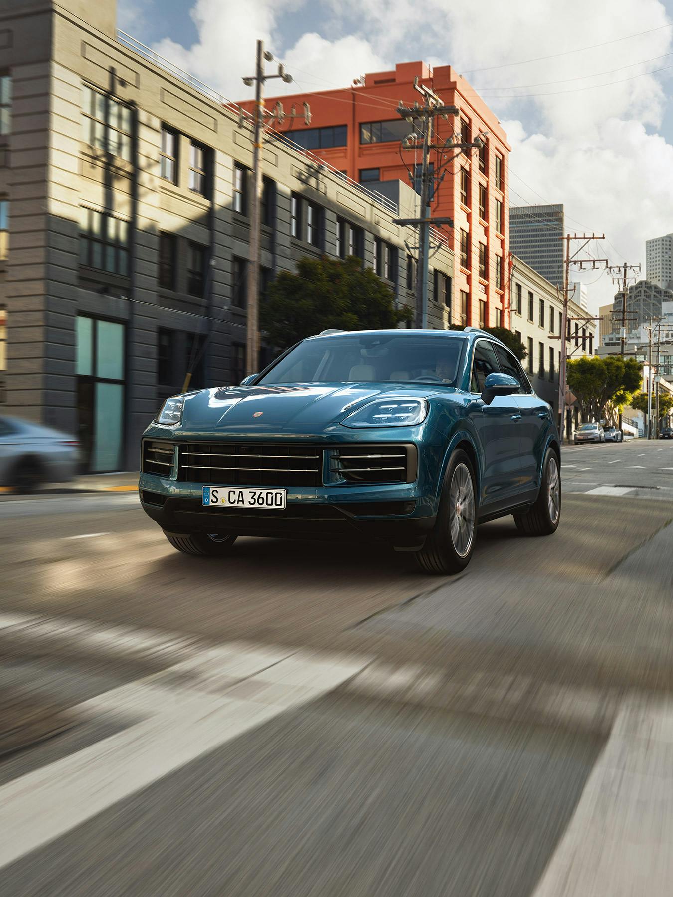 Ein blauer Porsche Cayenne fährt durch eine Stadtstraße.