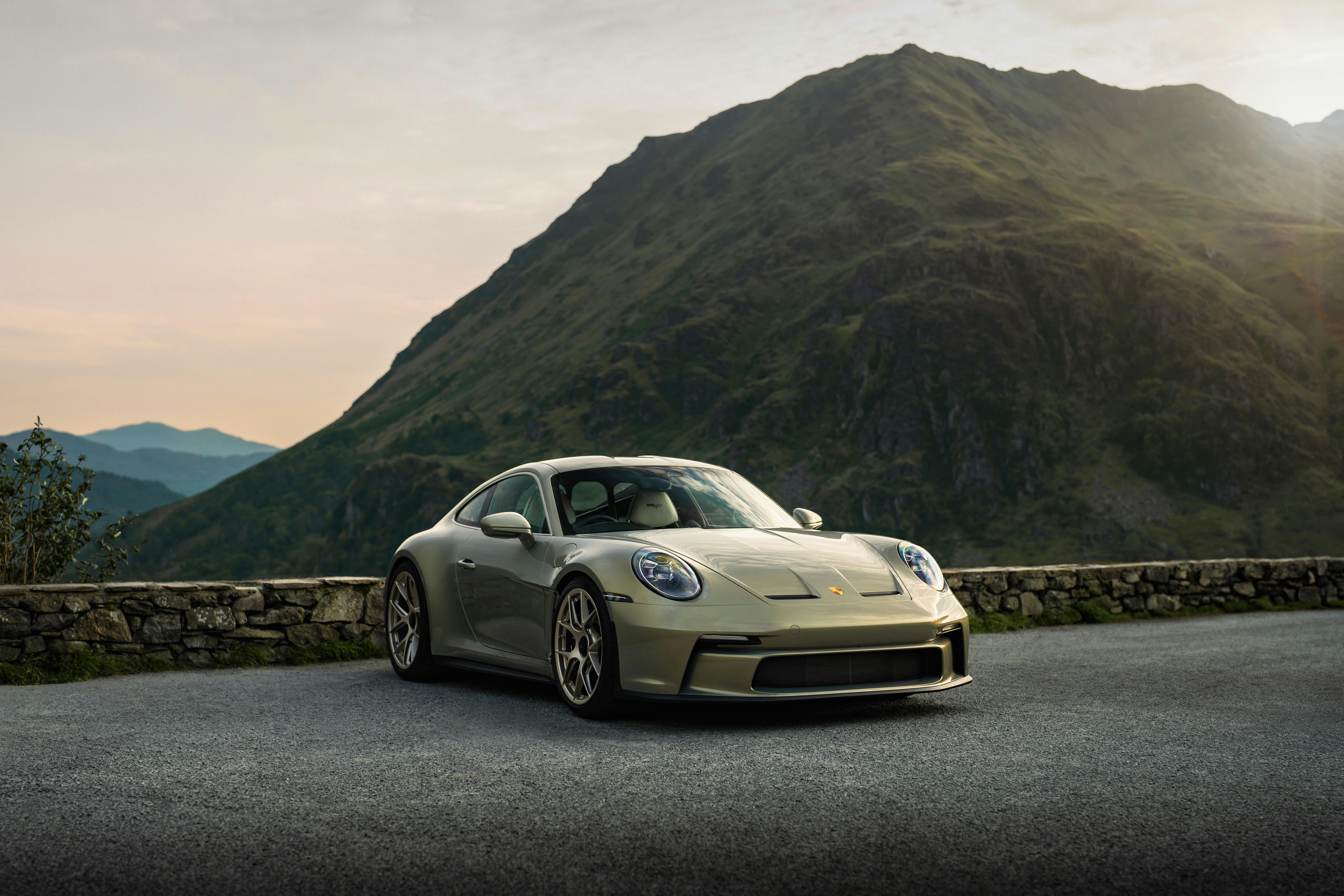 A car parked on the road with a mountain in the background. 
