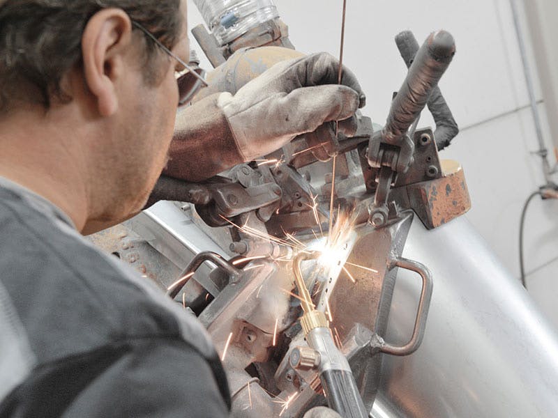 Workshop scene: man welds the front and main parts of the wing together, sparks.