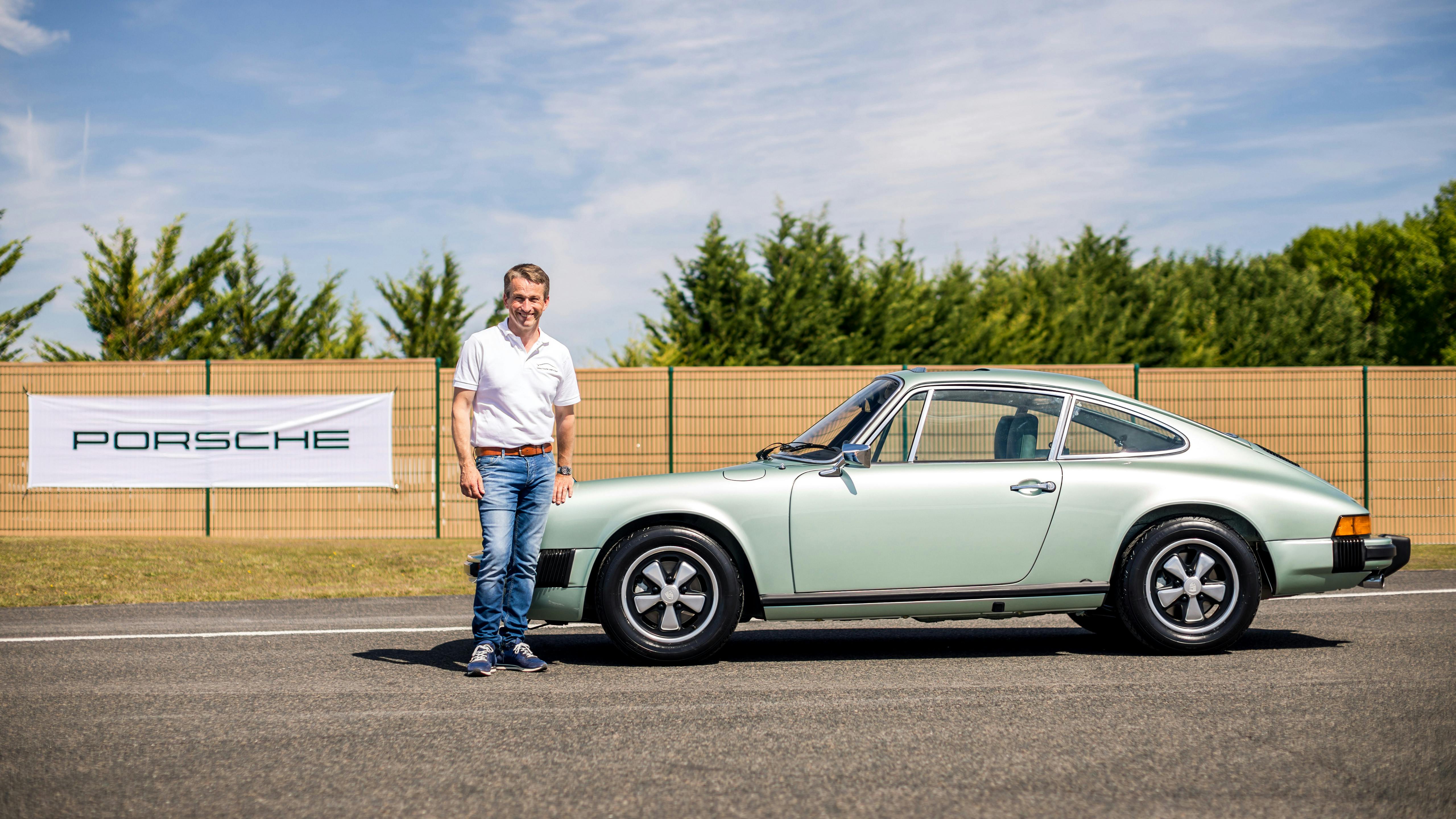 Le participant se tient à côté du véhicule gagnant dans la catégorie restauration complète, une Porsche 911 Speedster 3.2l.