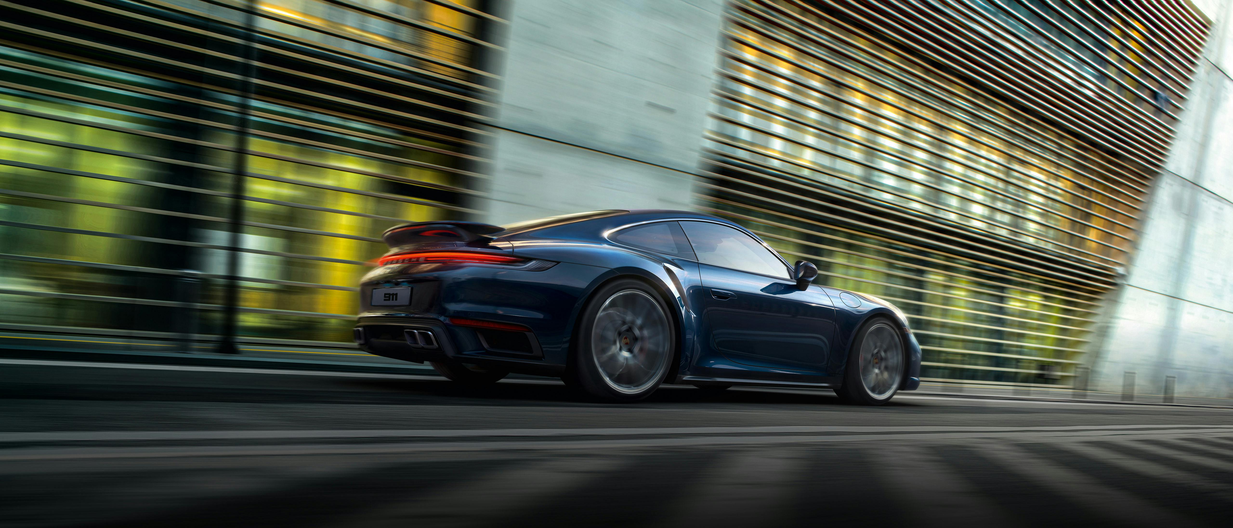 A sleek blue Porsche 911 speeding through a modern city street, showcasing its aerodynamic design and powerful performance.