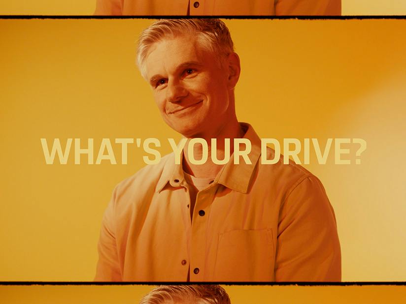 Porsche Mitarbeiter Stefan lächelt in einer Nahaufnahme in die Kamera. Das Bild ist überblendet mit einem Schriftzug "What's Your Drive?".