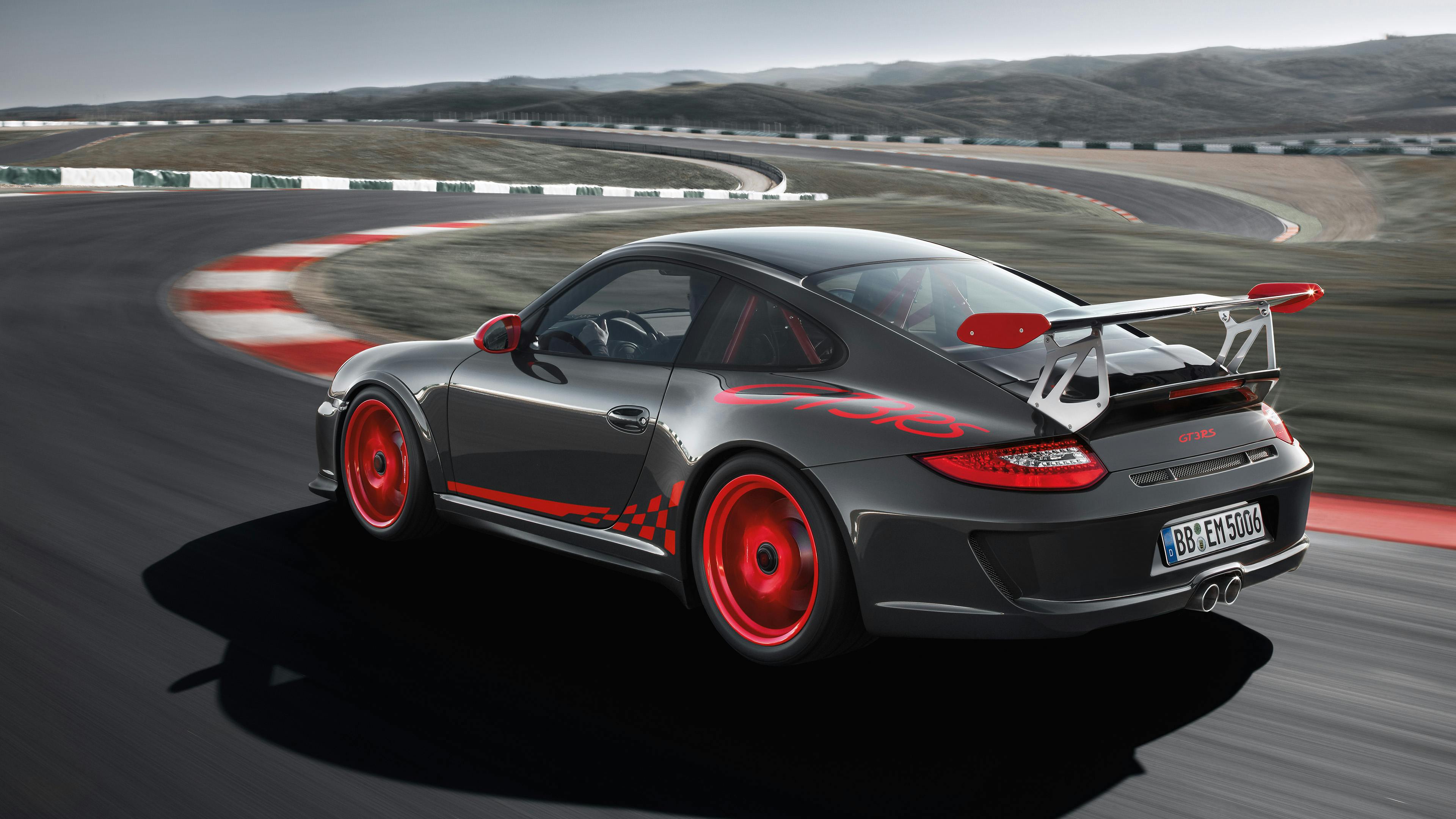 Driving black 911 GT3 RS type 997 on a race track.