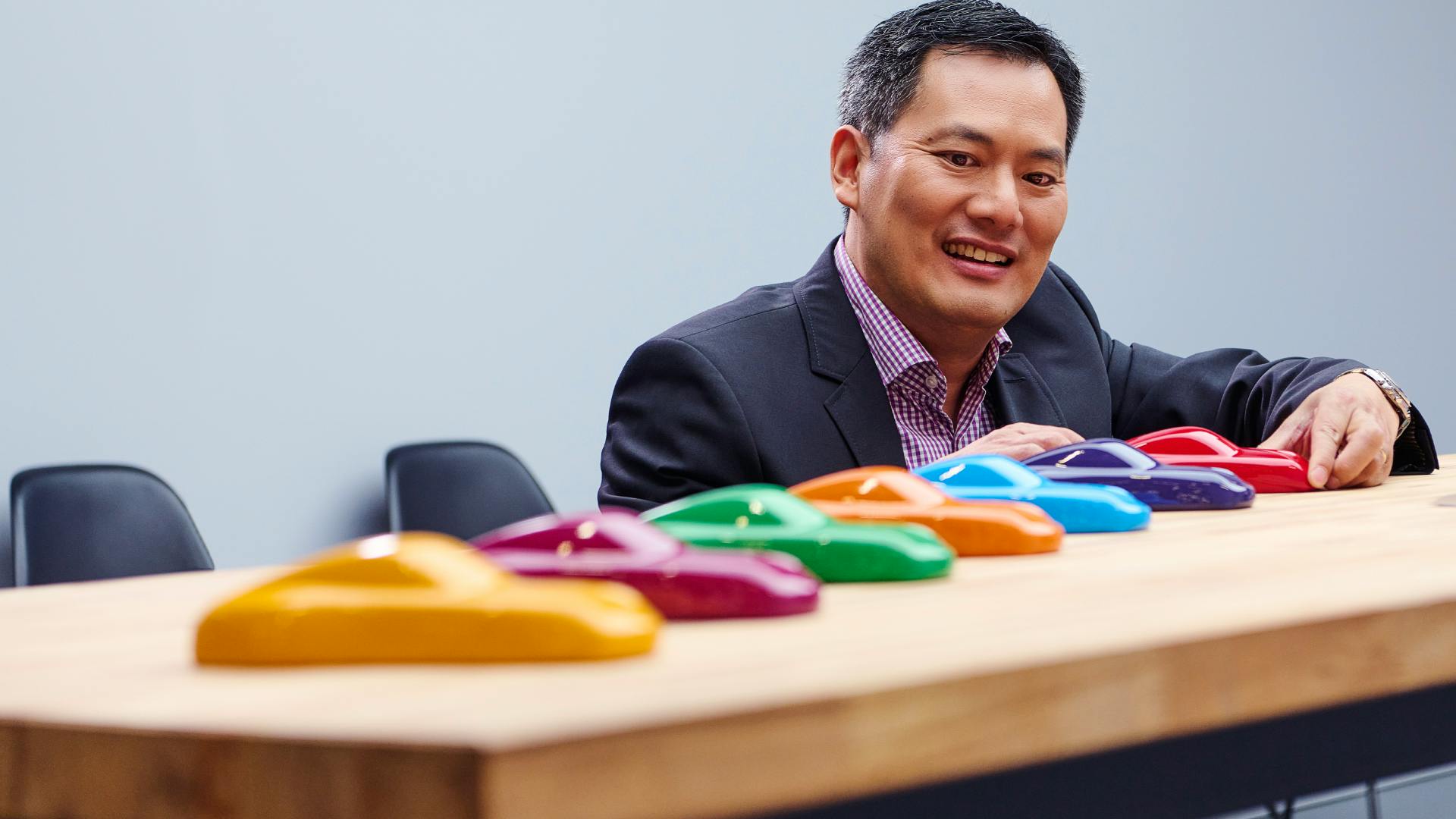 Dreams in Colours: Close-up of paint samples in the form of 911 silhouettes in different strong colours placed in a row with President Vutthikorn Inthraphuvasak in the background.