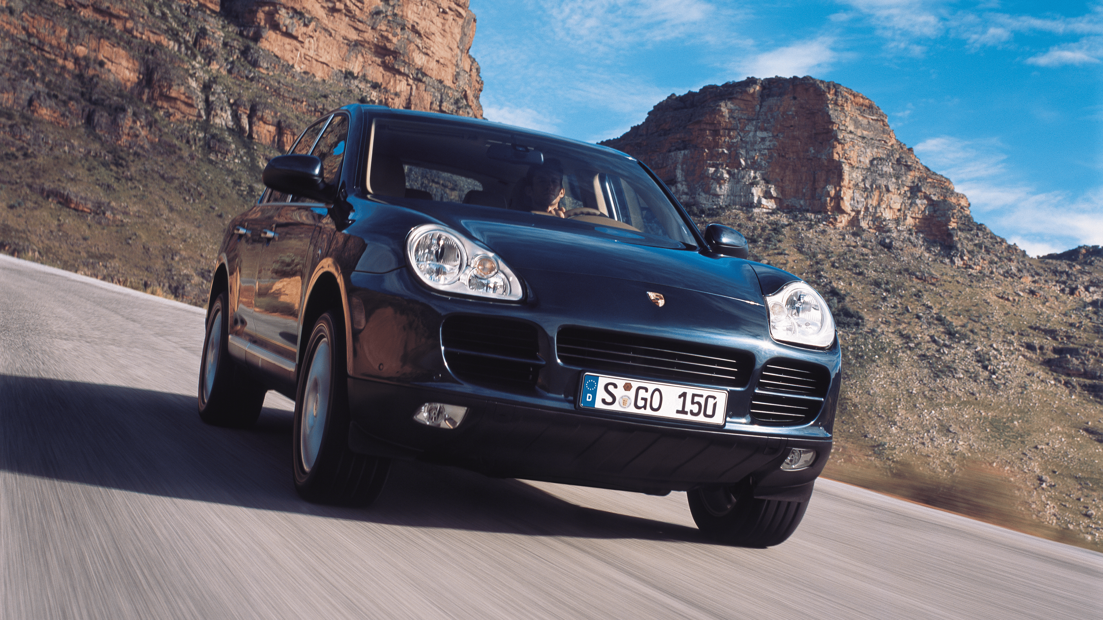 Black Porsche Cayenne S driving in front of mountains