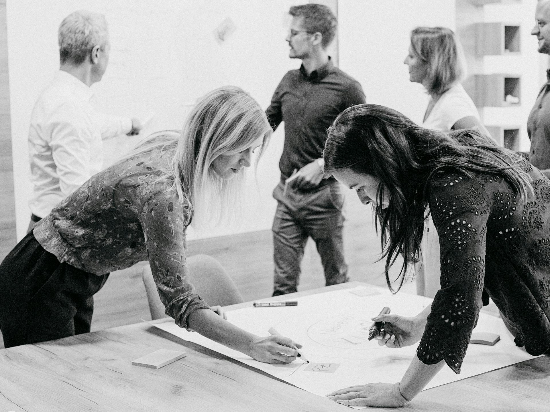 Black-and-white photo: Porsche employees plan together in a workshop.