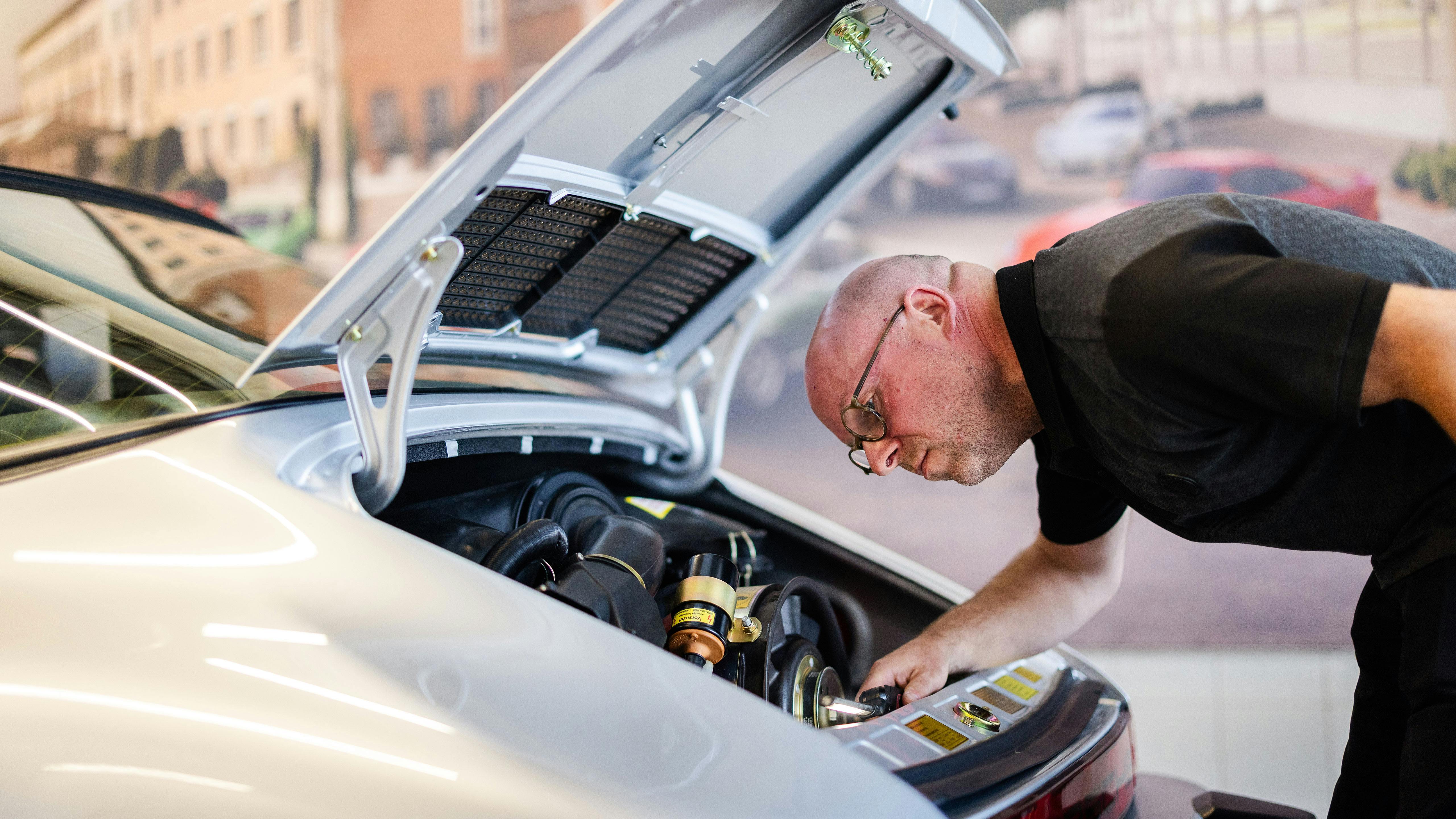 Un membre du jury inspectant une porsche participante