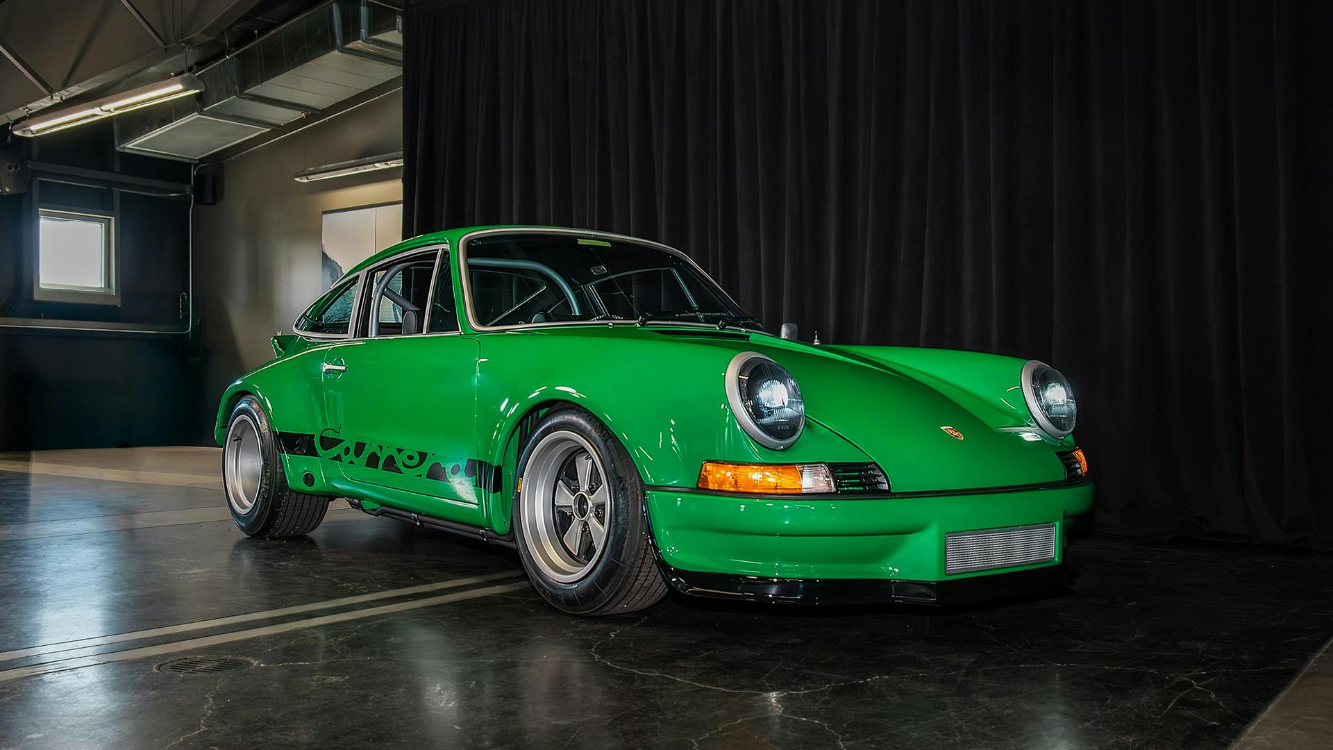 A vibrant green vintage 911 sports car with round headlights is parked indoors on a polished floor.