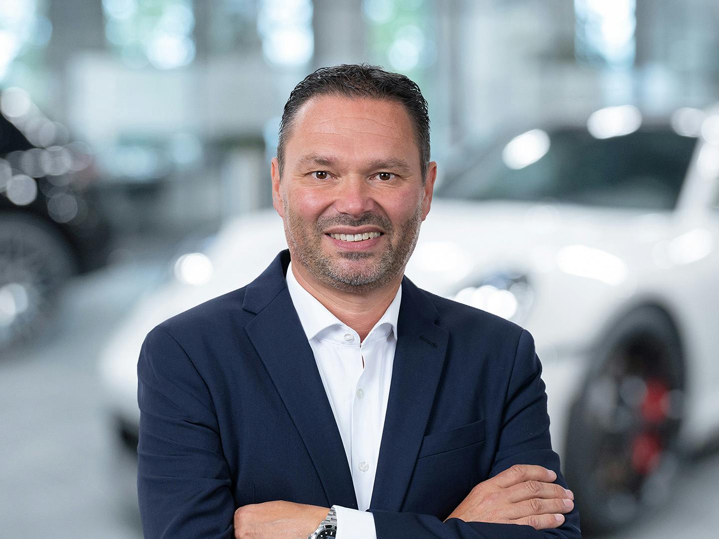 Porsche Mitarbeiterin berät einen Kunden der in einem Porsche Fahrzeug sitzt.