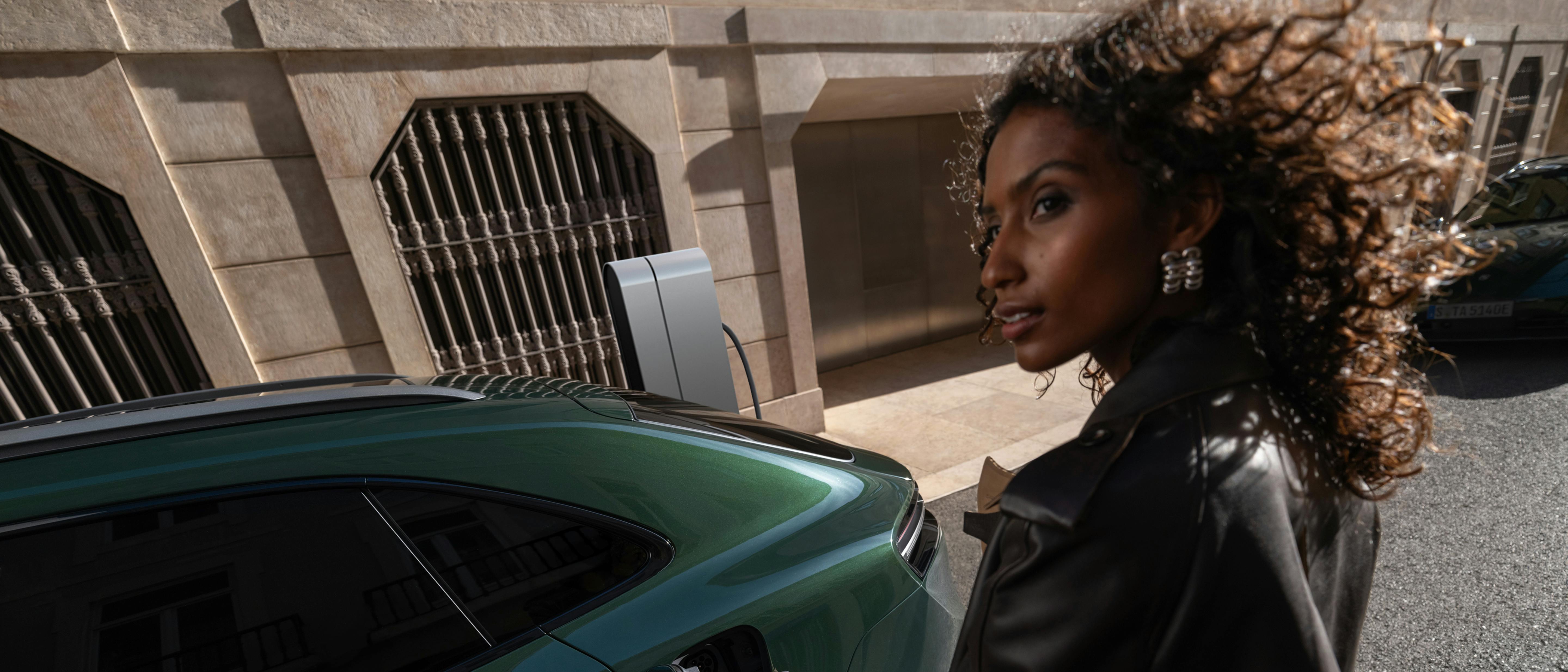 A woman plugging a charging plug into the charging socket of a Porsche Macan 4S.