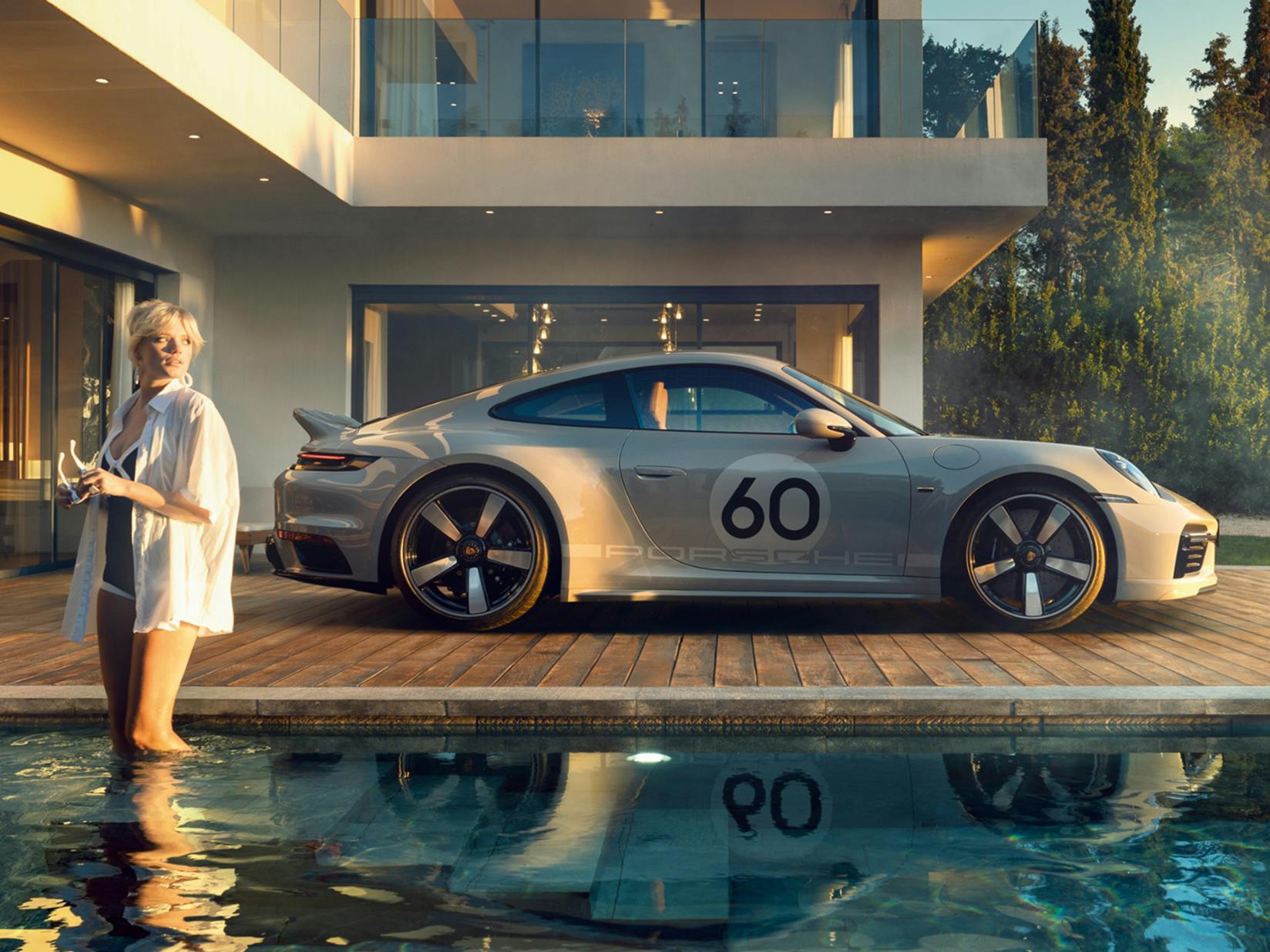 Porsche 911 Sport Classic in Sport Grey Metallic by the pool in front of a villa. Side view.