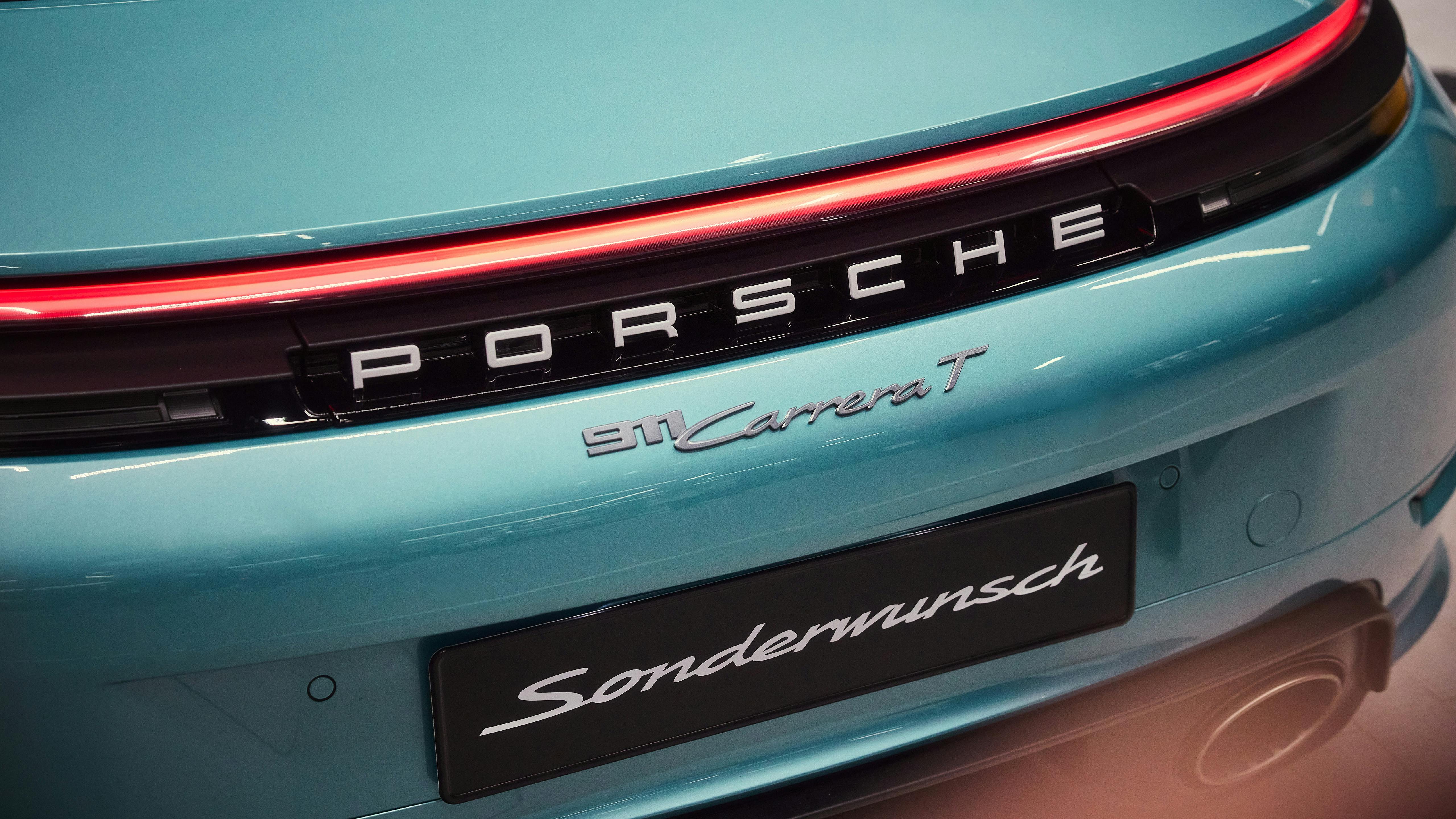 Rear view of a Porsche 911 Carrera T in turquoise, with illuminated light strip and Sonderwunsch badge.