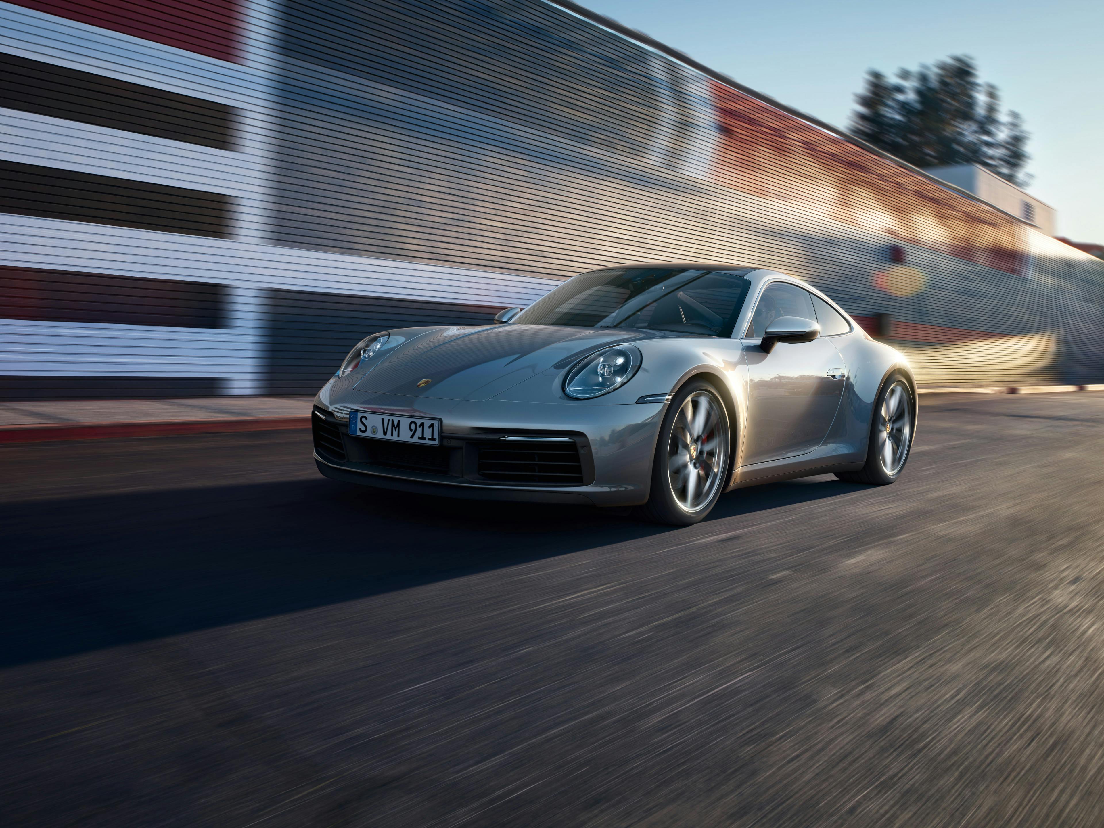 A silver 911 driving along a street.