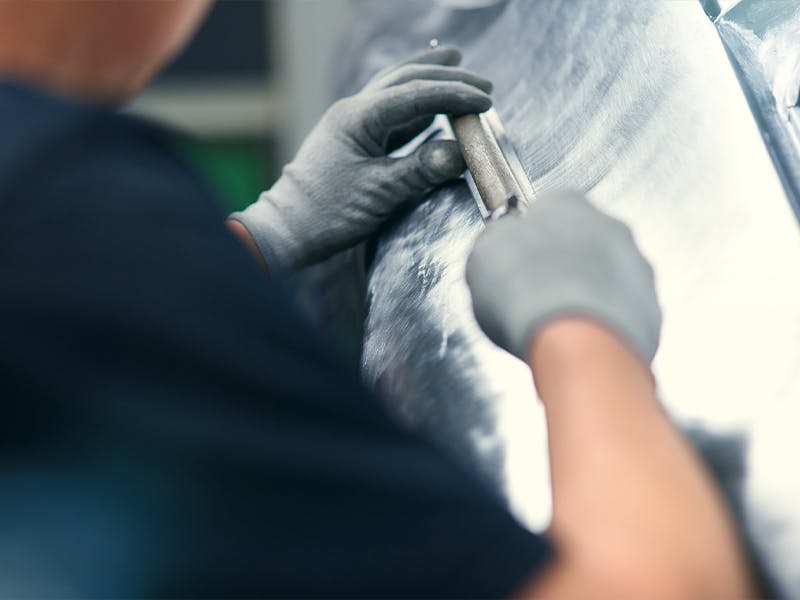 Factory restoration employee working on the body of a classic vehicle