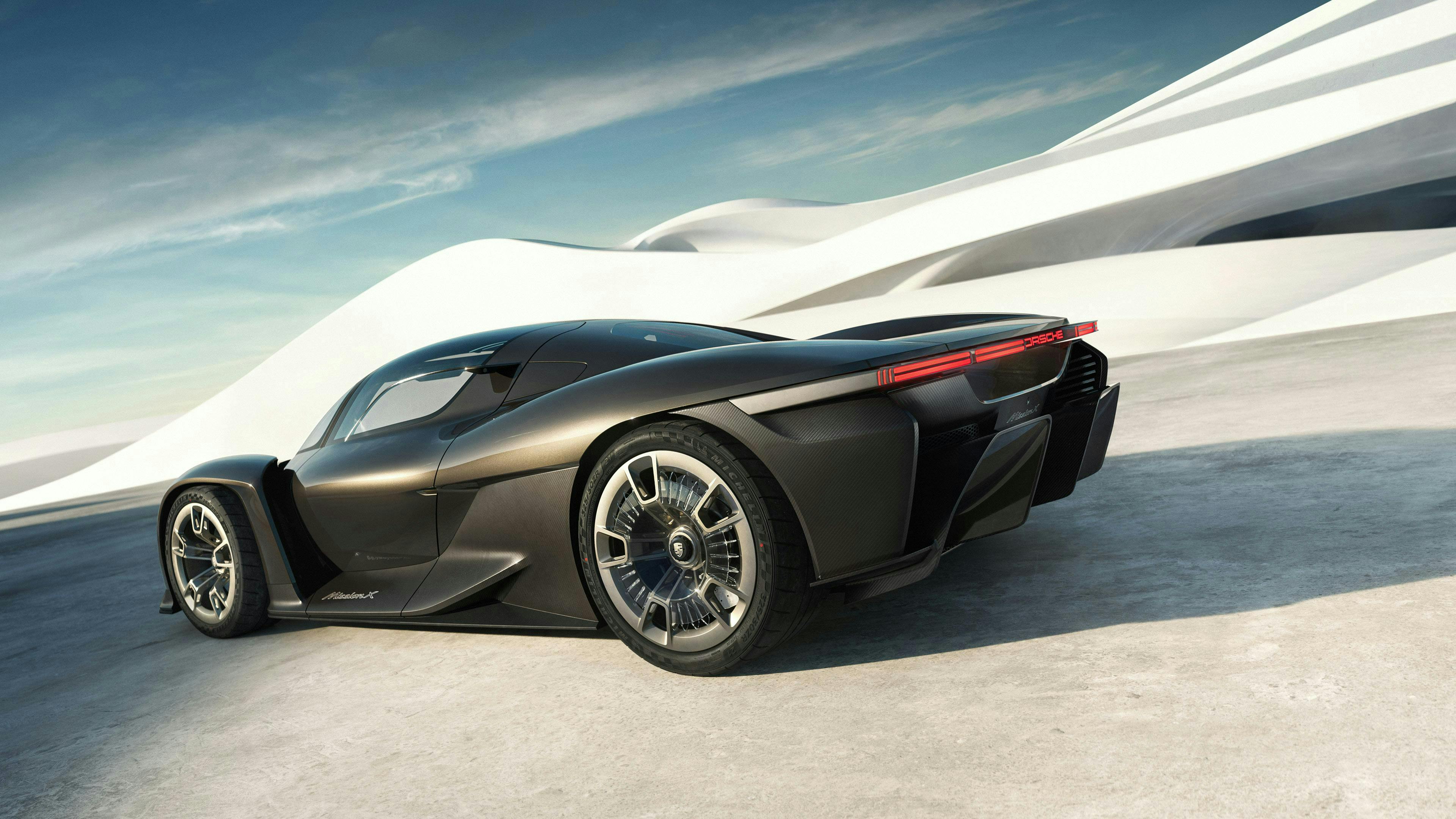 波のような建築物の前に停まっているロケットメタリックのPorsche Mission X リアビューとサイドビュー