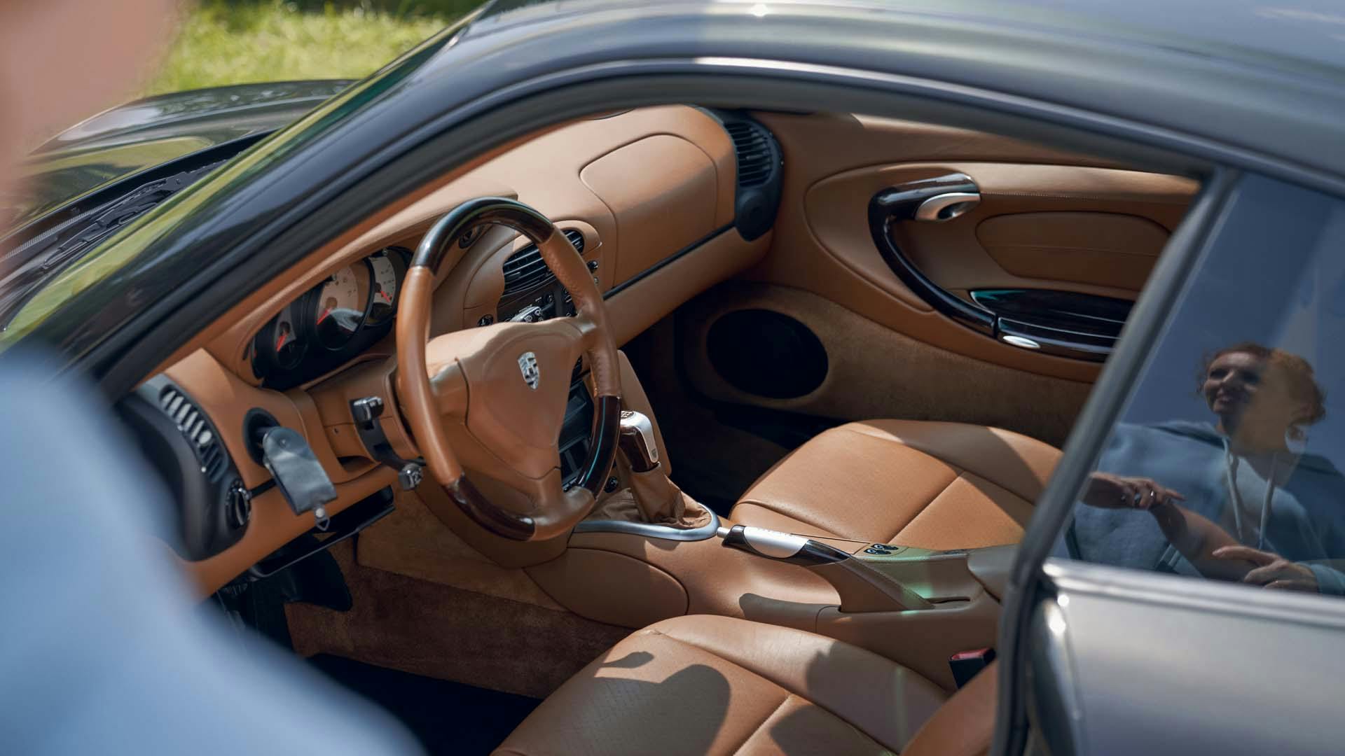 Frau spiegelt sich in der Scheibe eines Fahrzeugs mit rotbraunem Interieur