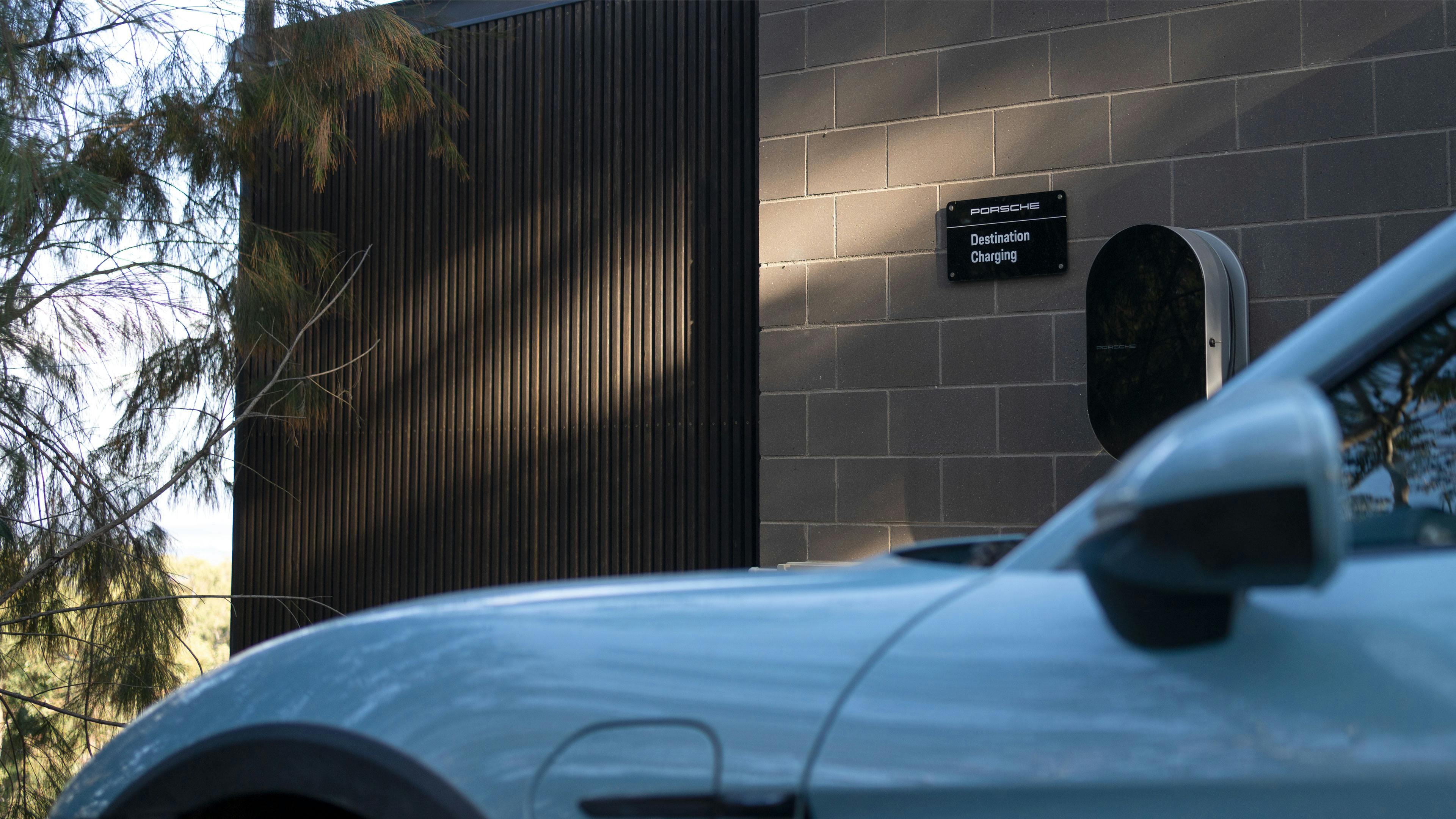 Porsche Taycan parked in next to porsche charging destination in bush area