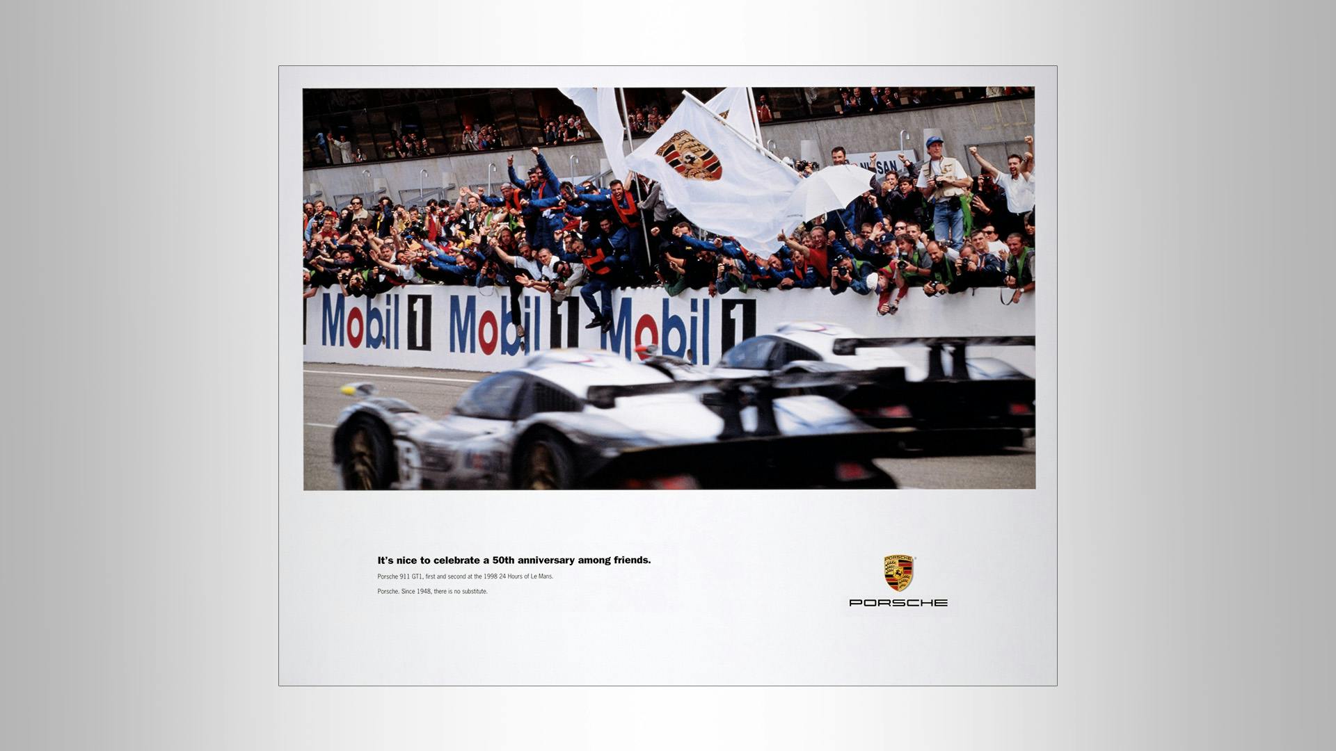 Porsche birthdayposter from 1998 with a fast Porsche racing car on the race track and many people cheering: It's nice to celebrate a 50th anniversary among friends. Porsche 911 GTI, first an second at the 1998 24 Hours of Le Mans. Porsche. Since 1984, there is no substitute.