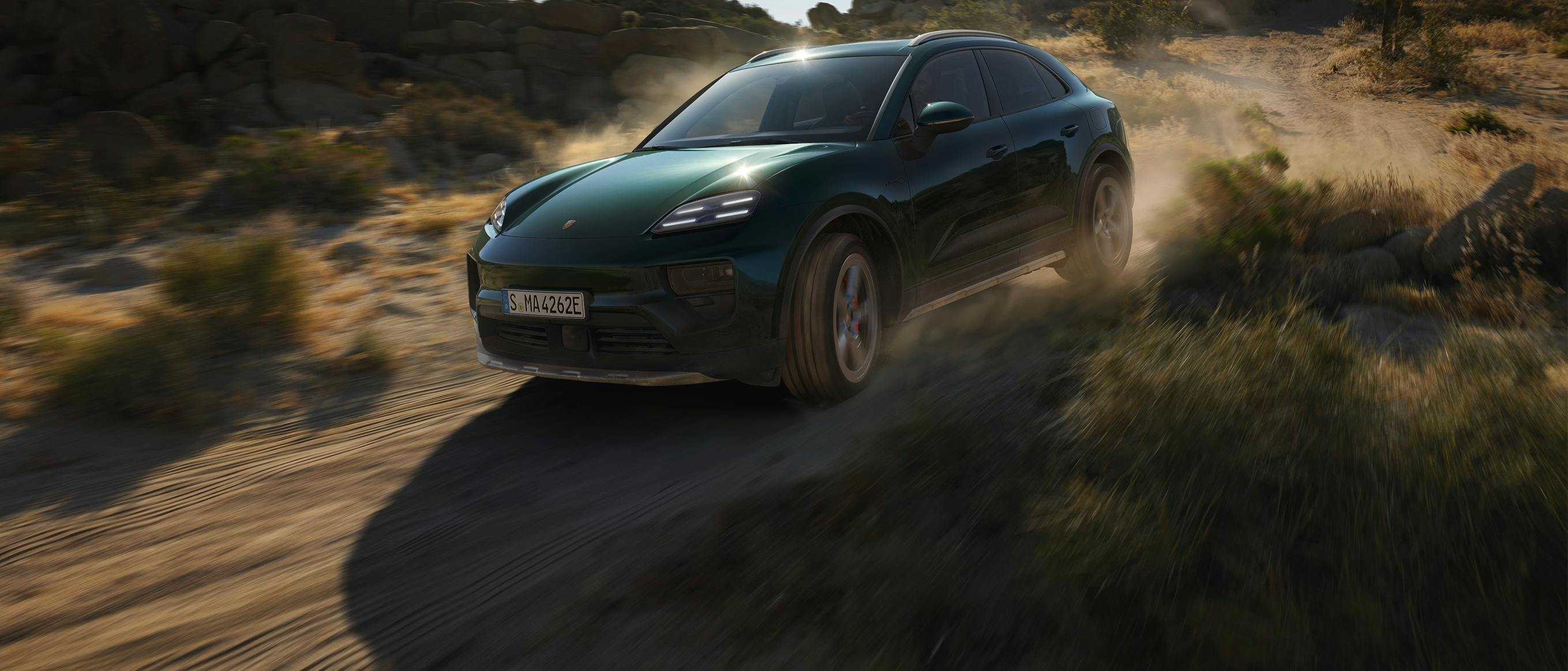 Um Porsche Macan 4S a circular numa estrada de terra batida, levantando poeira.