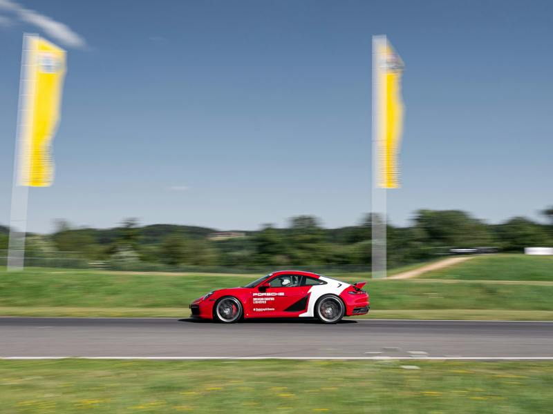 Une voiture de sport Porsche 911 rouge en pleine course sur la piste.